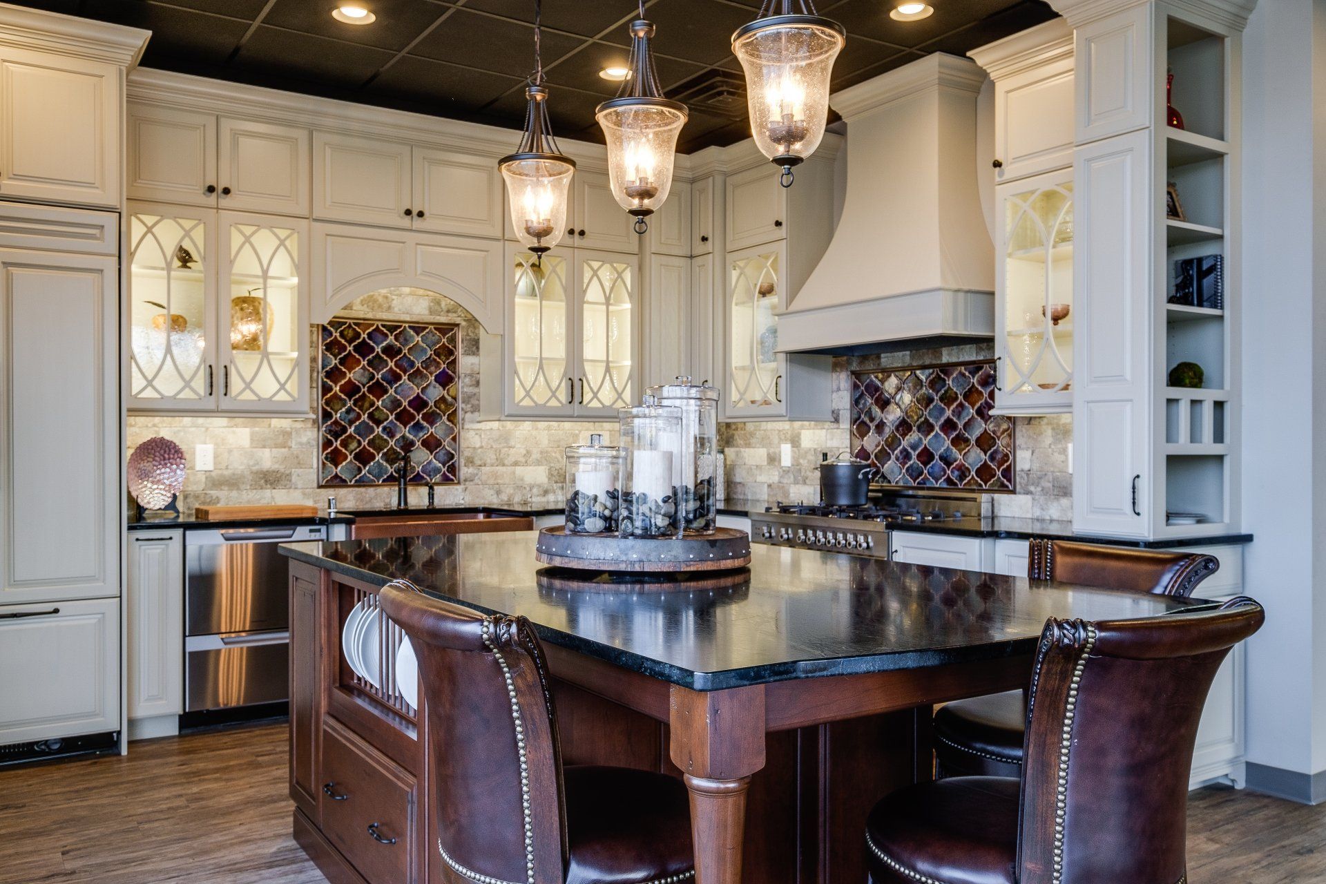 Elegant white kitchen with dark island, leather stools, and pendant lights