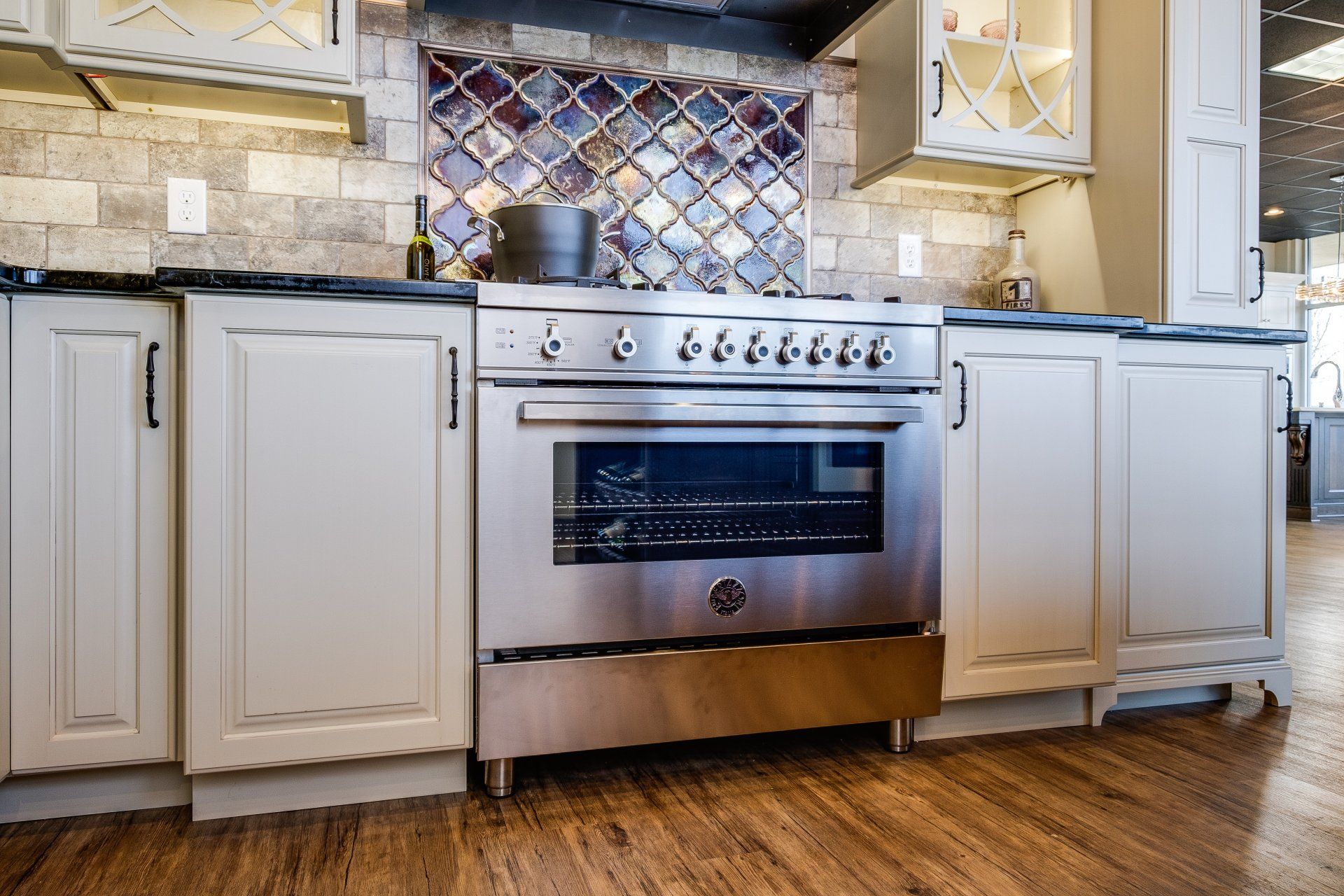 Modern kitchen with white cabinets, stainless steel oven, and wood floor