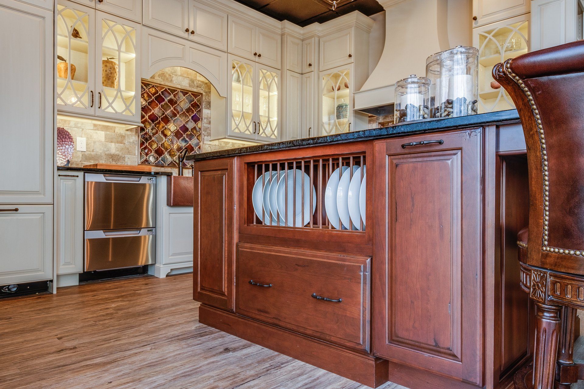 Bright kitchen with white cabinets, stainless steel fridge, and dark wood island with dish rack display