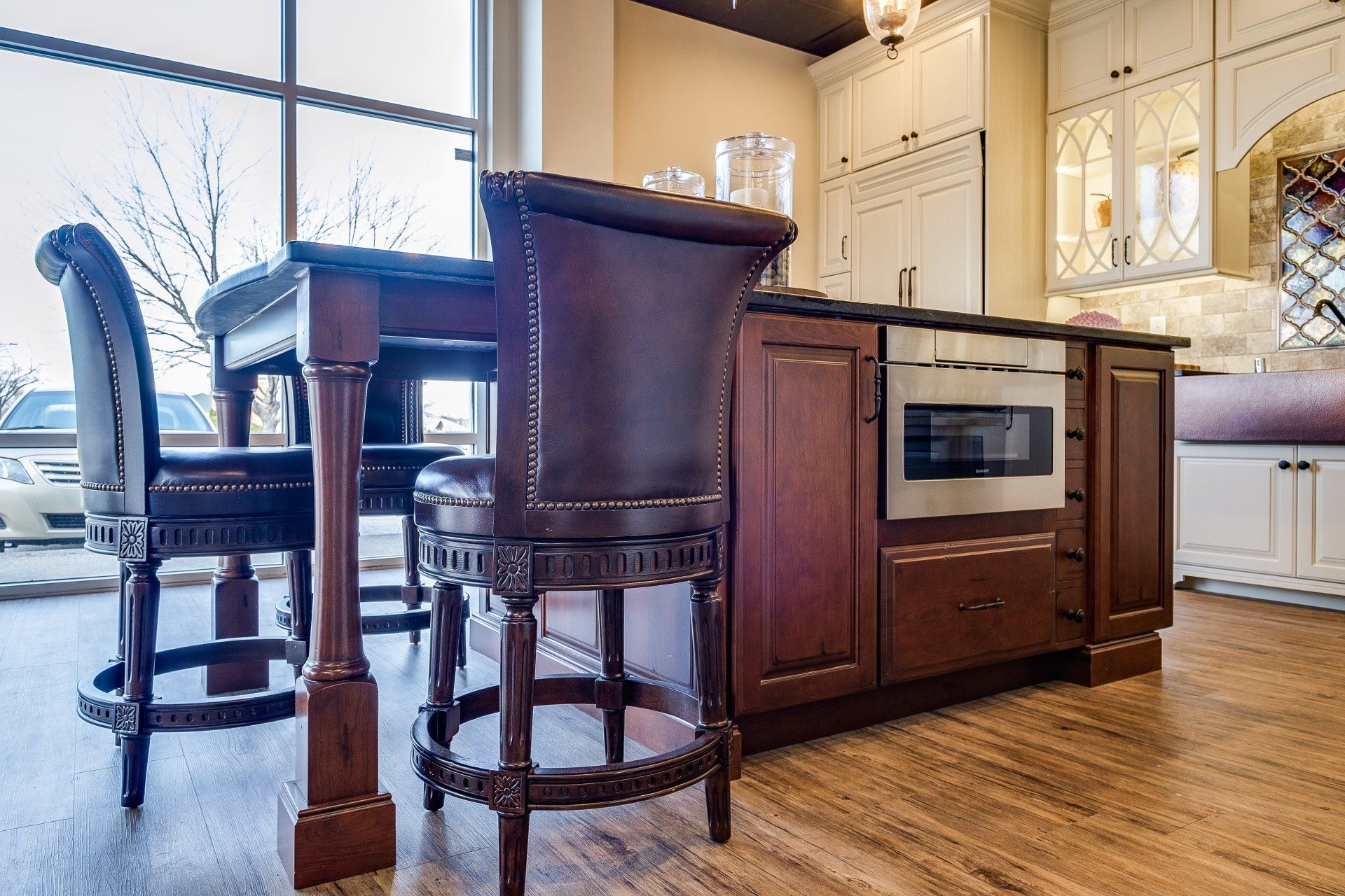 Kitchen island with two bar stools, built-in oven, and hardwood floors in a bright home interior