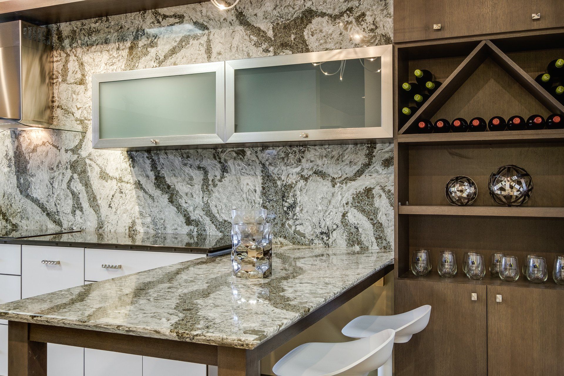 Modern kitchen with granite island, frosted cabinets, and a built-in wine shelf