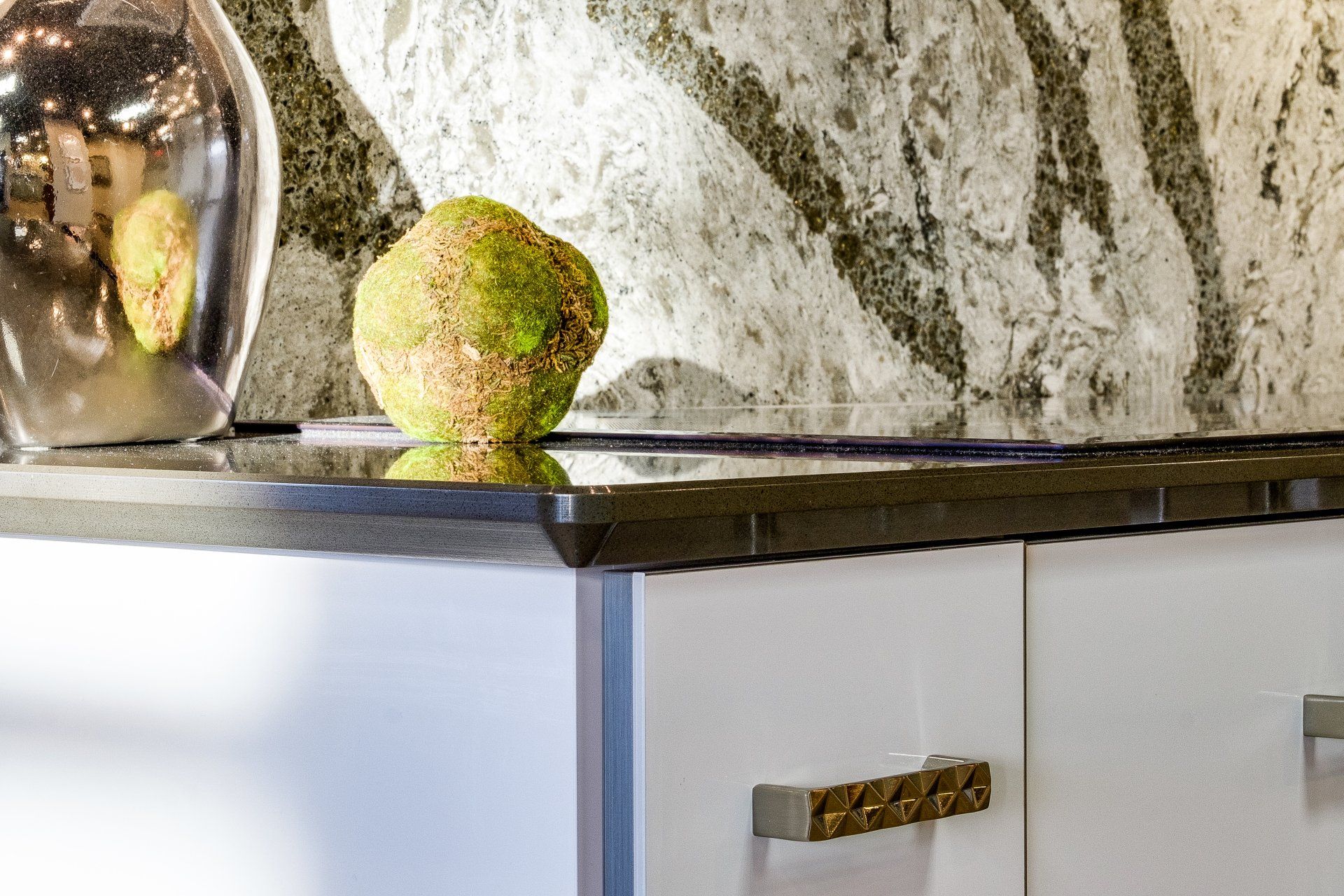 Kitchen countertop with a green pear, glass bowl, and marble backsplash