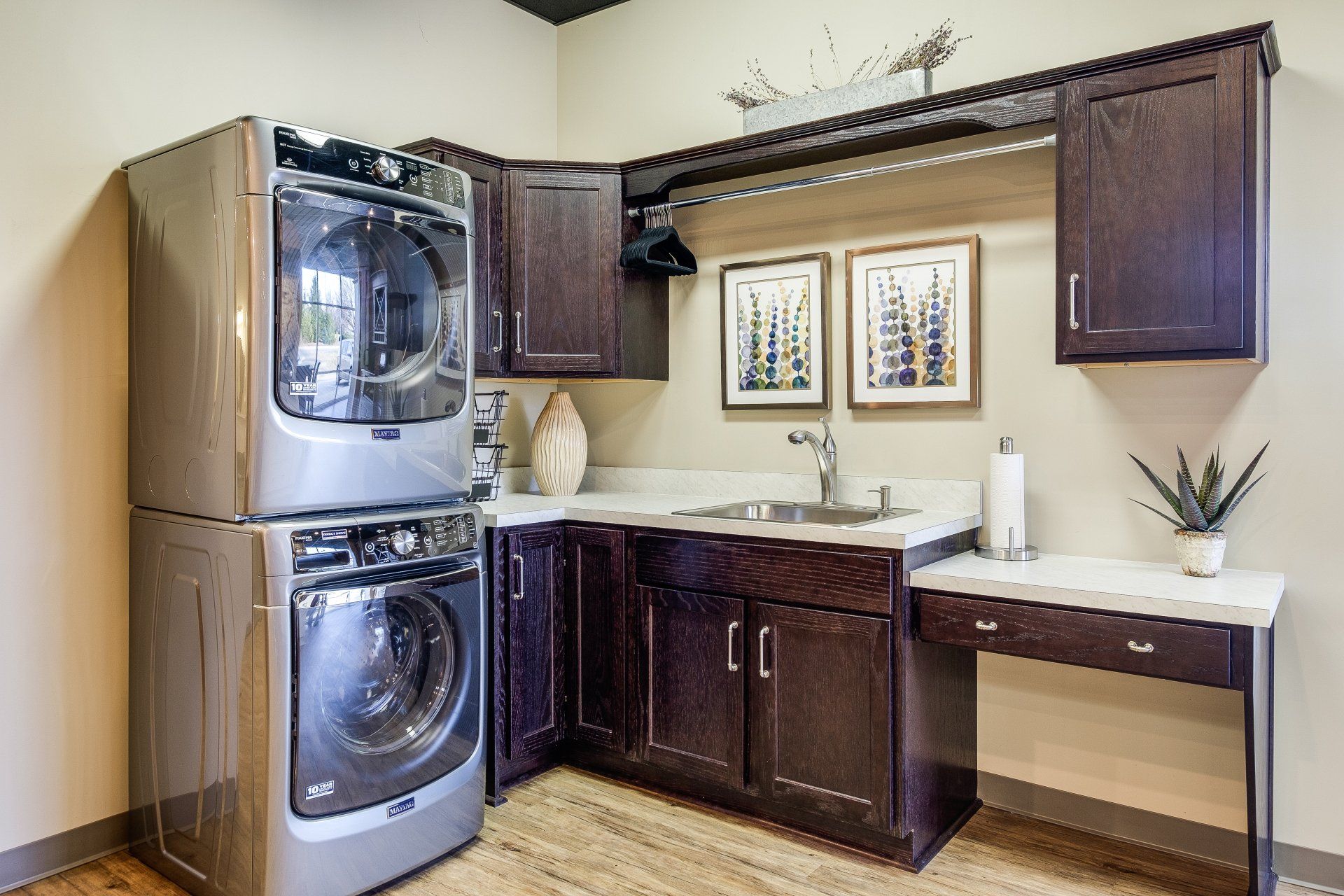 Laundry room with stacked washer-dryer beside a dark wood sink cabinet and countertop.