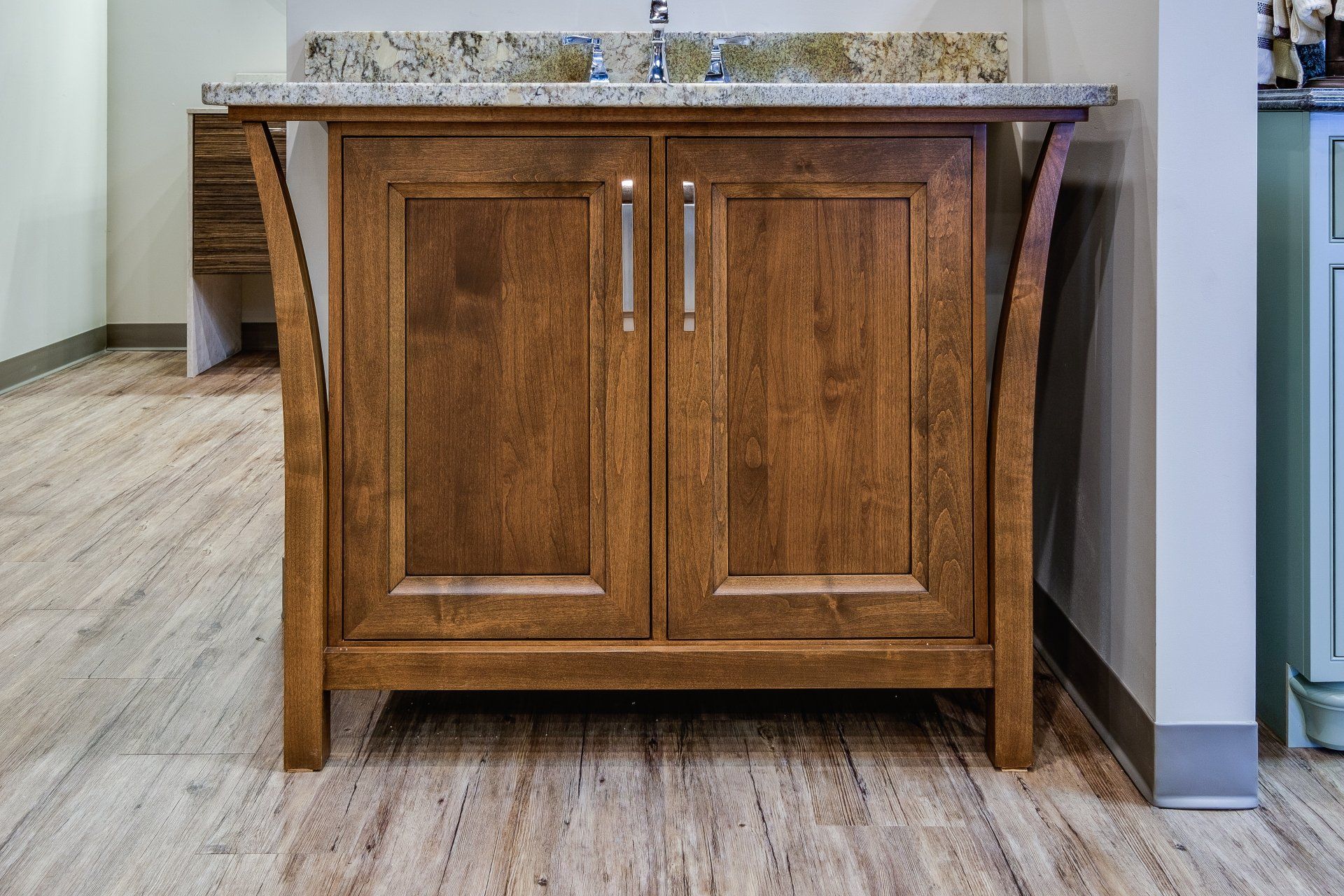 Wooden bathroom vanity with granite countertop and a centered sink in a tiled room