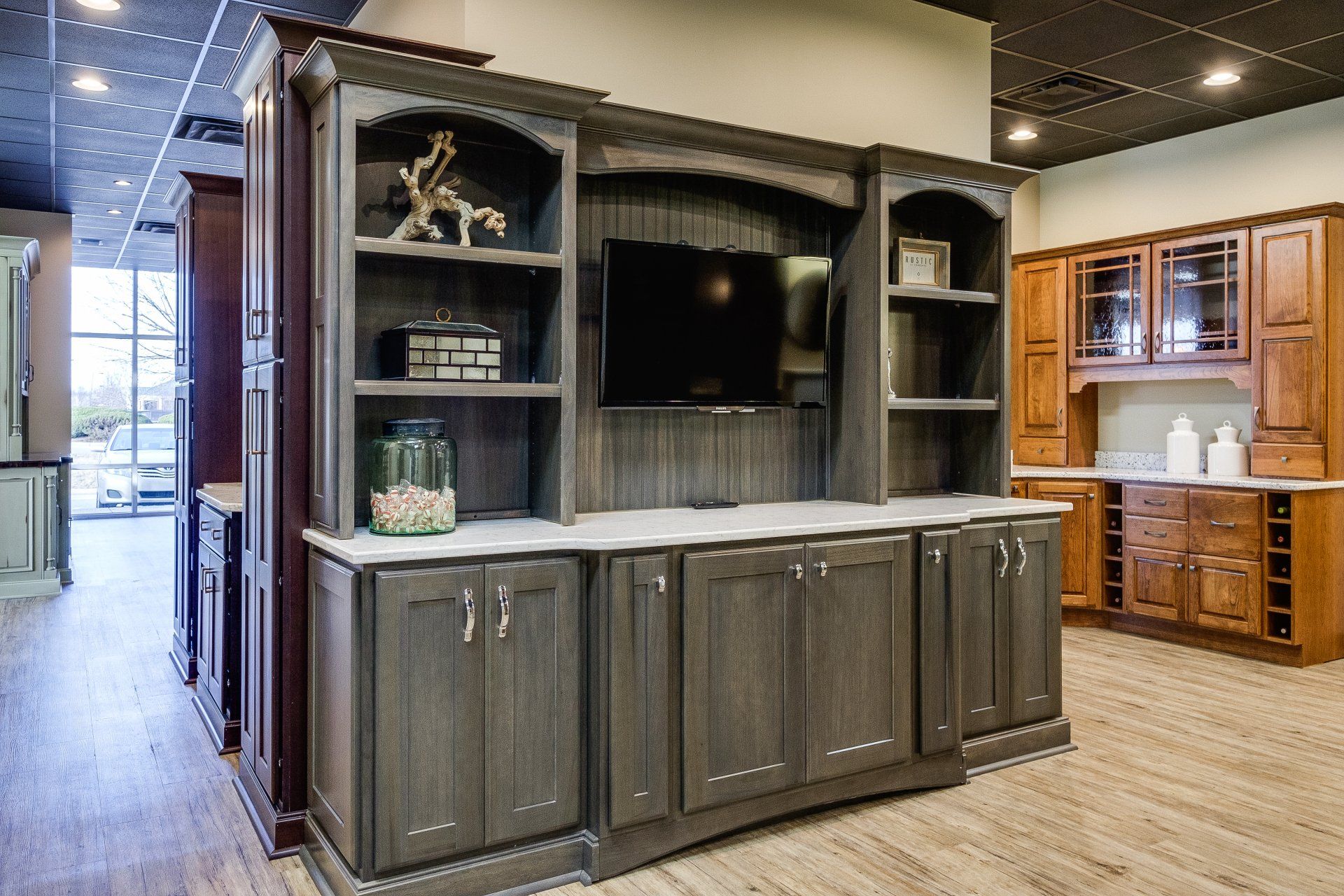Built-in gray entertainment cabinet with TV, shelves, and storage in a showroom kitchen display