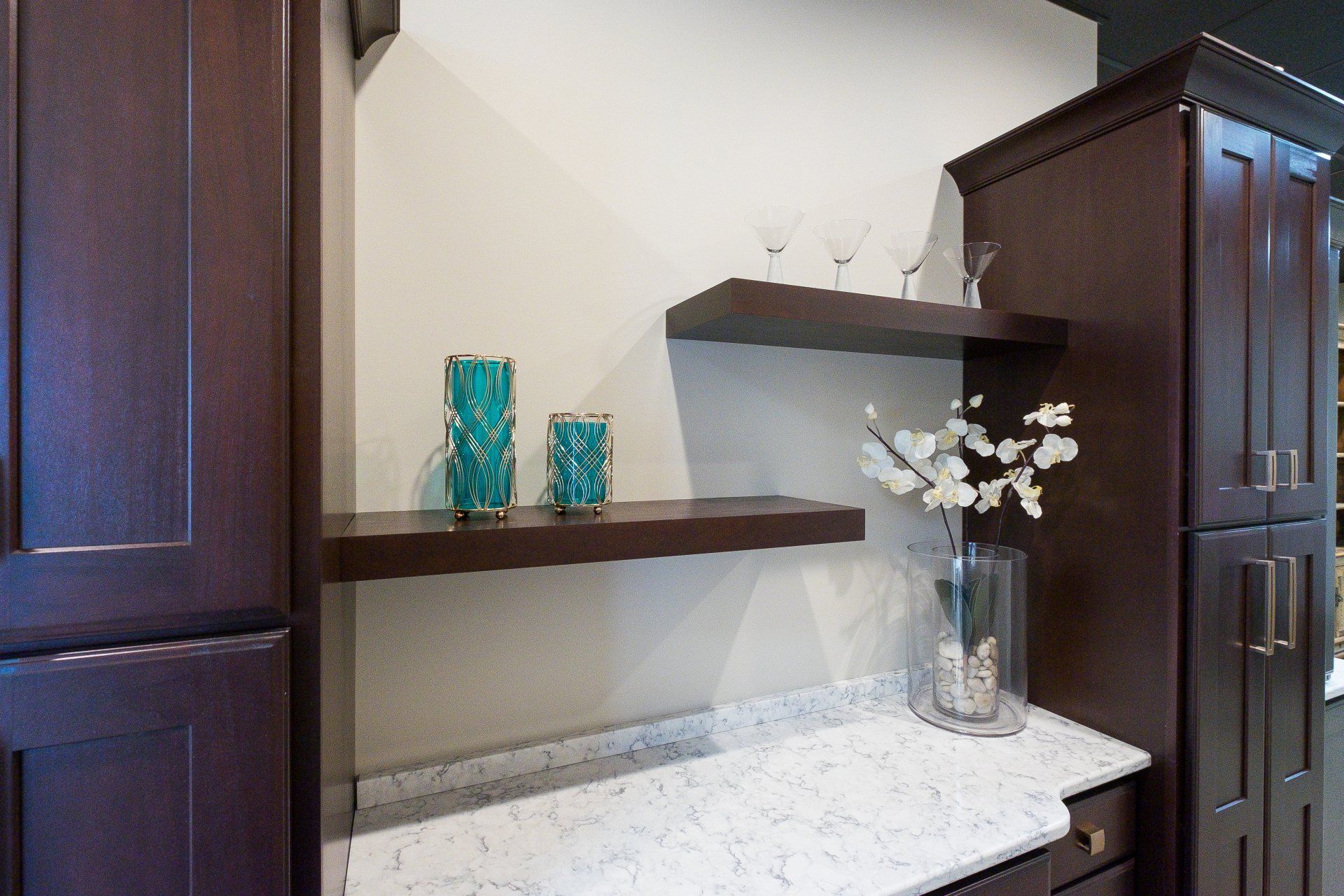 Built-in desk nook with dark wood shelves, white marble counter, and turquoise vases with white flowers