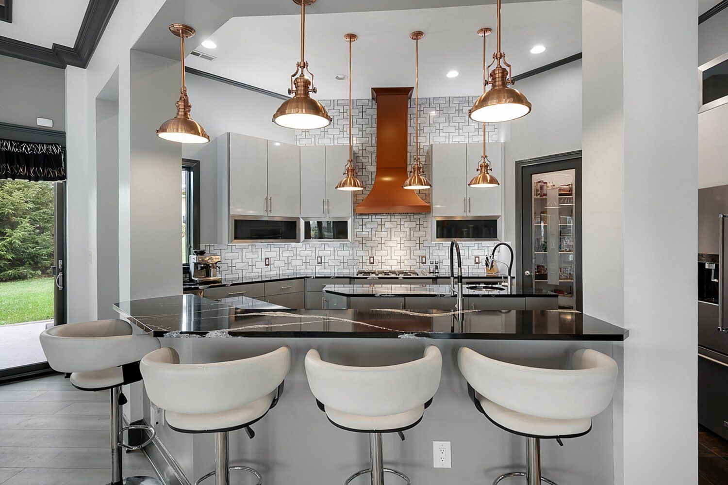 Modern kitchen with island barstools, pendant lights, and stainless steel appliances