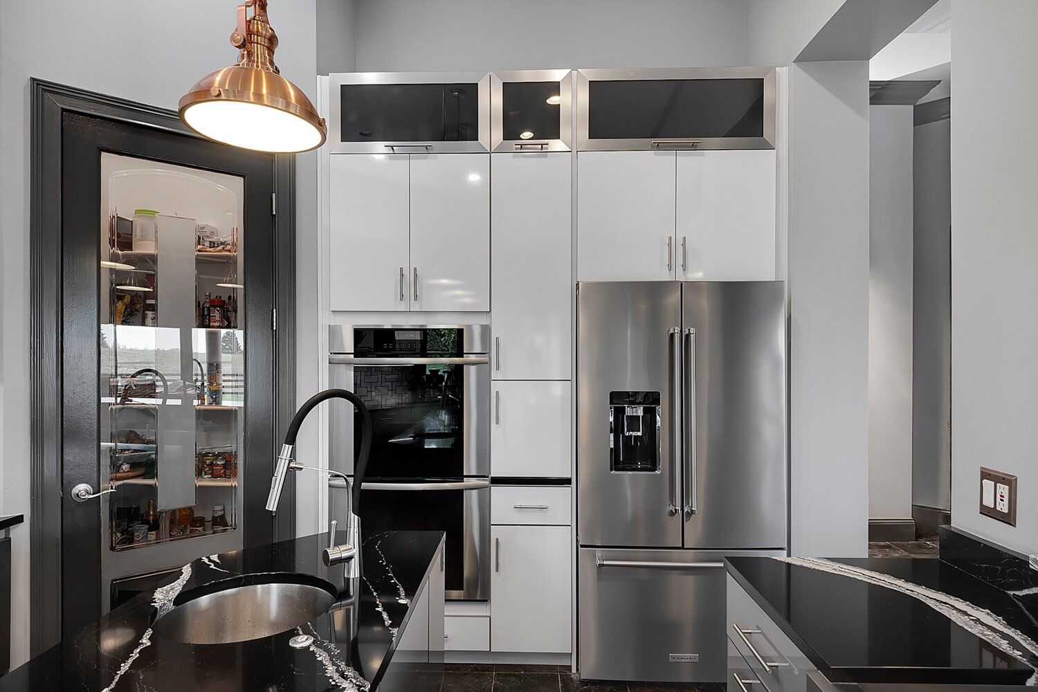 Modern kitchen with stainless steel appliances, white cabinets, black granite counters, and pendant lighting