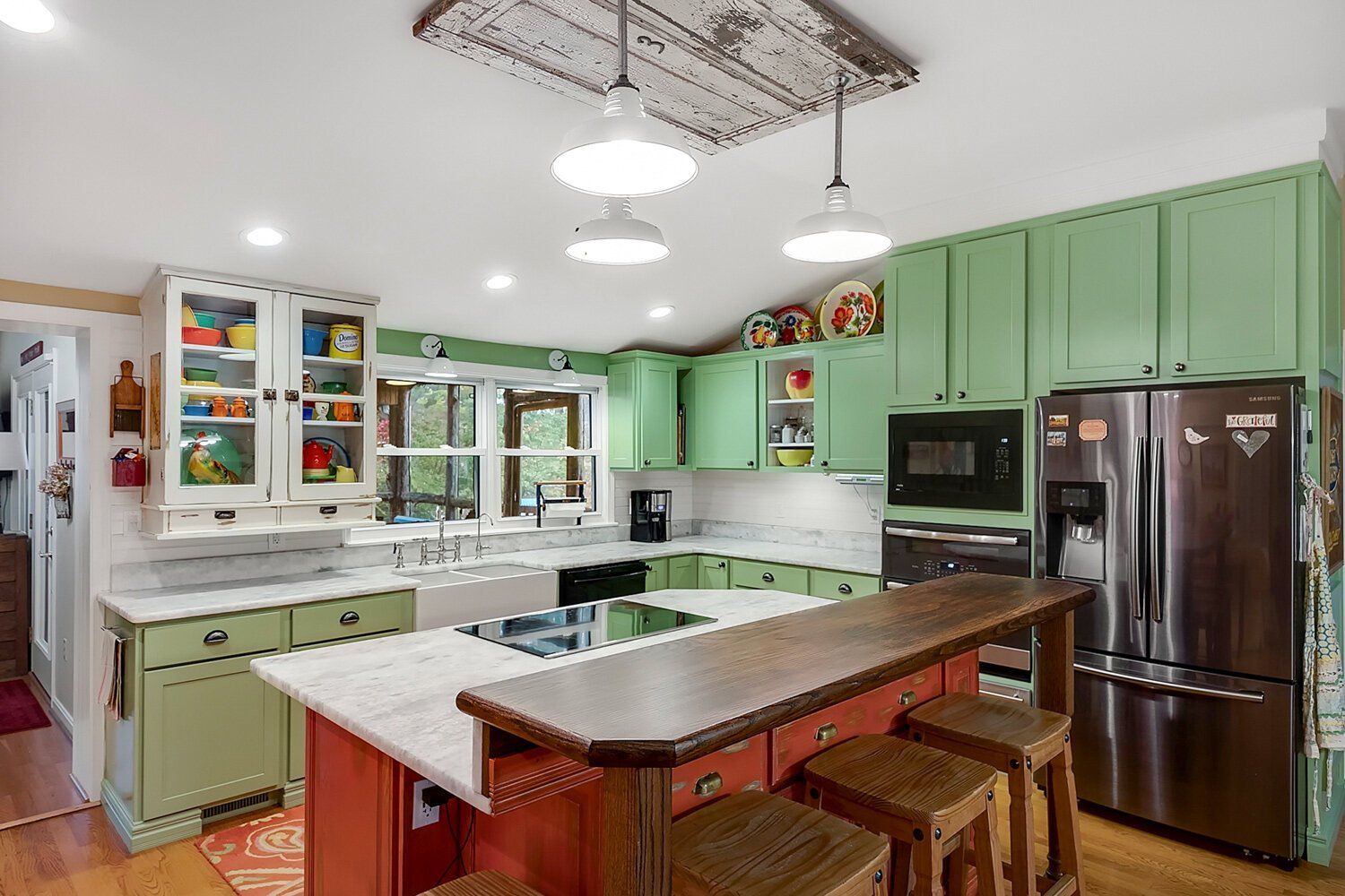 Bright mint-green kitchen with white cabinets, island, and stainless-steel appliances