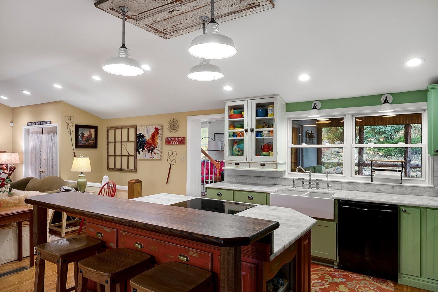 Bright kitchen with island, white cabinets, pendant lights, and a window over the sink