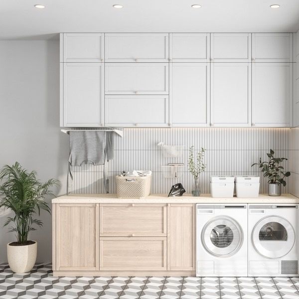 Bright modern laundry room with white cabinets, wood counter, and stacked washer-dryer units