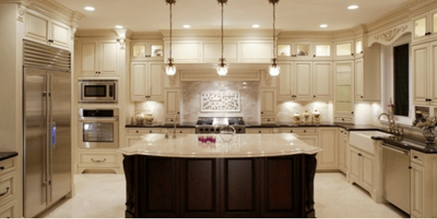 Elegant beige kitchen with a large island, pendant lights, and built-in stainless steel appliances