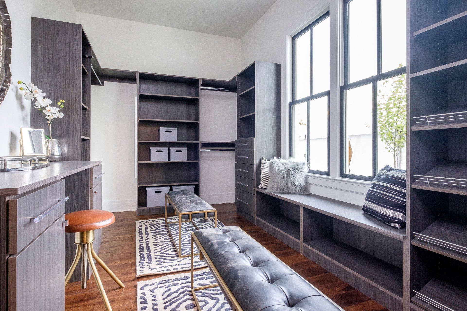 Modern home office with built-in shelves, desk, window seat, gray bench, and patterned rug