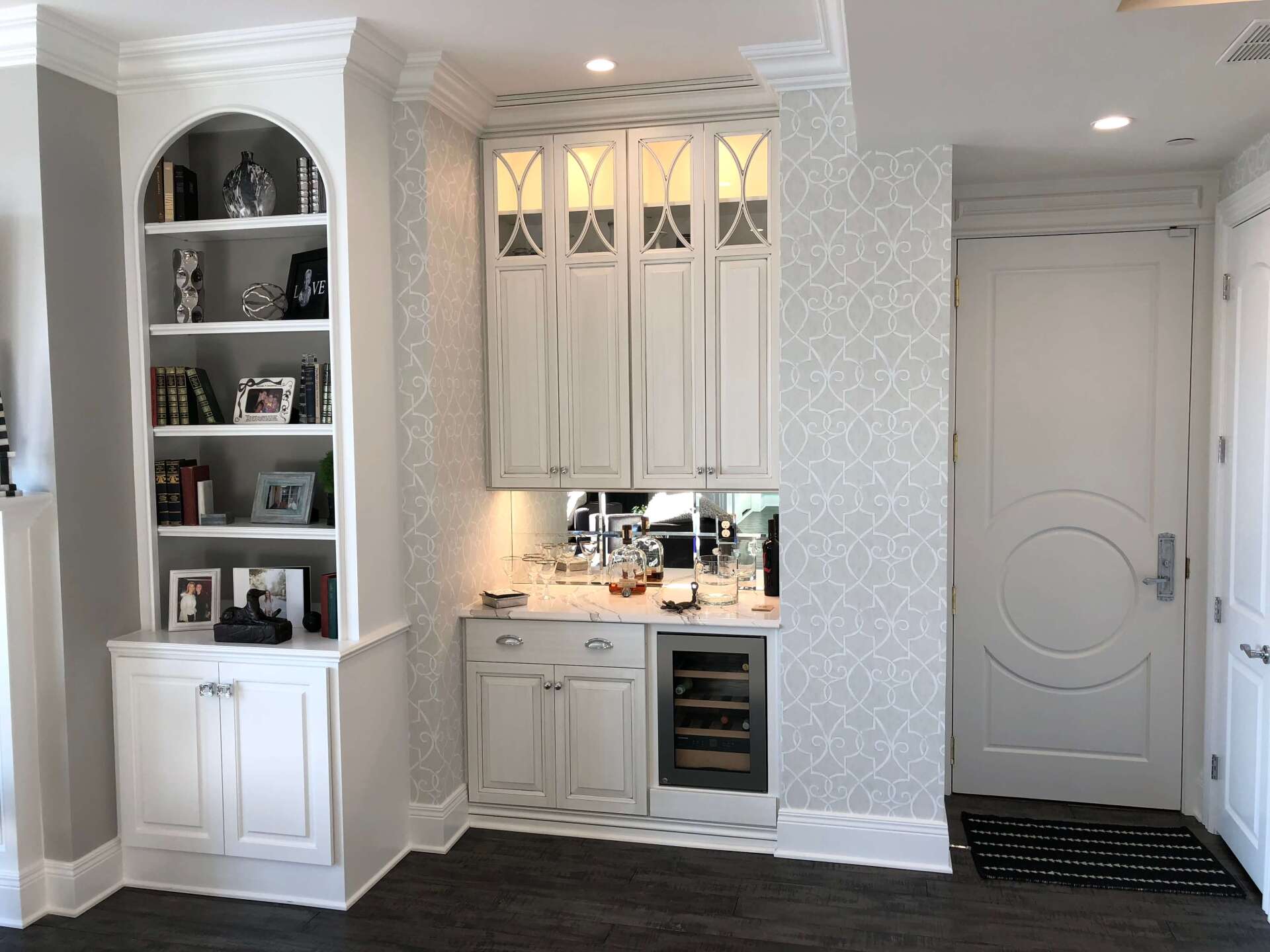 Bright white kitchen nook with built-in shelves, glass-front cabinets, and a small under-cabinet bar area