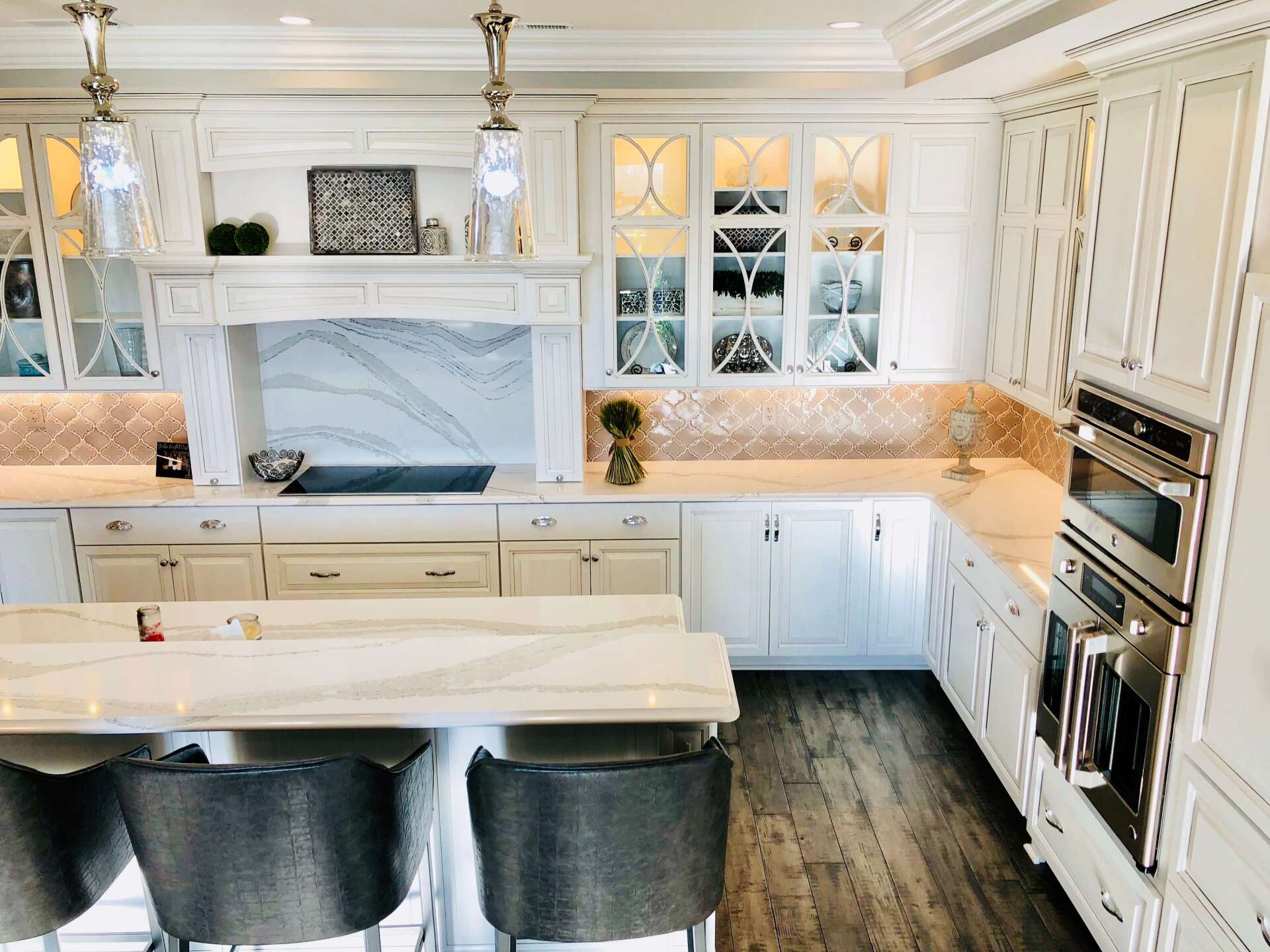 Bright white luxury kitchen with marble island, black stools, and built-in cabinets