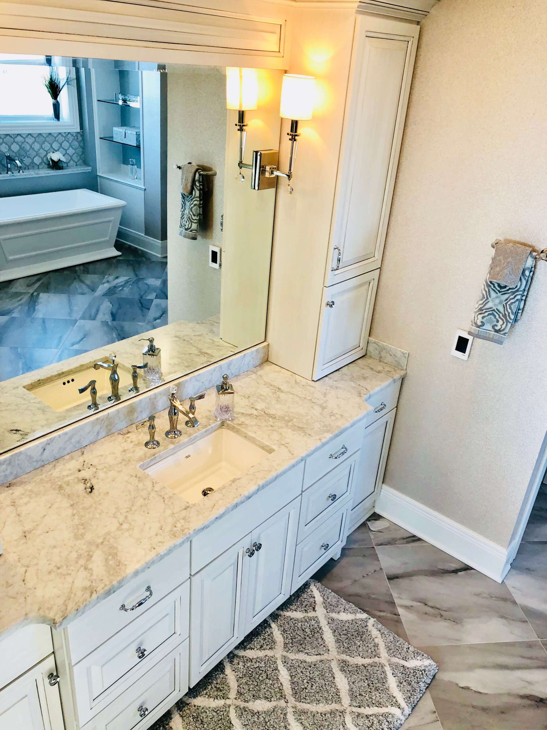 Elegant bathroom vanity with marble countertop, large mirror, wall sconces, and tiled floor