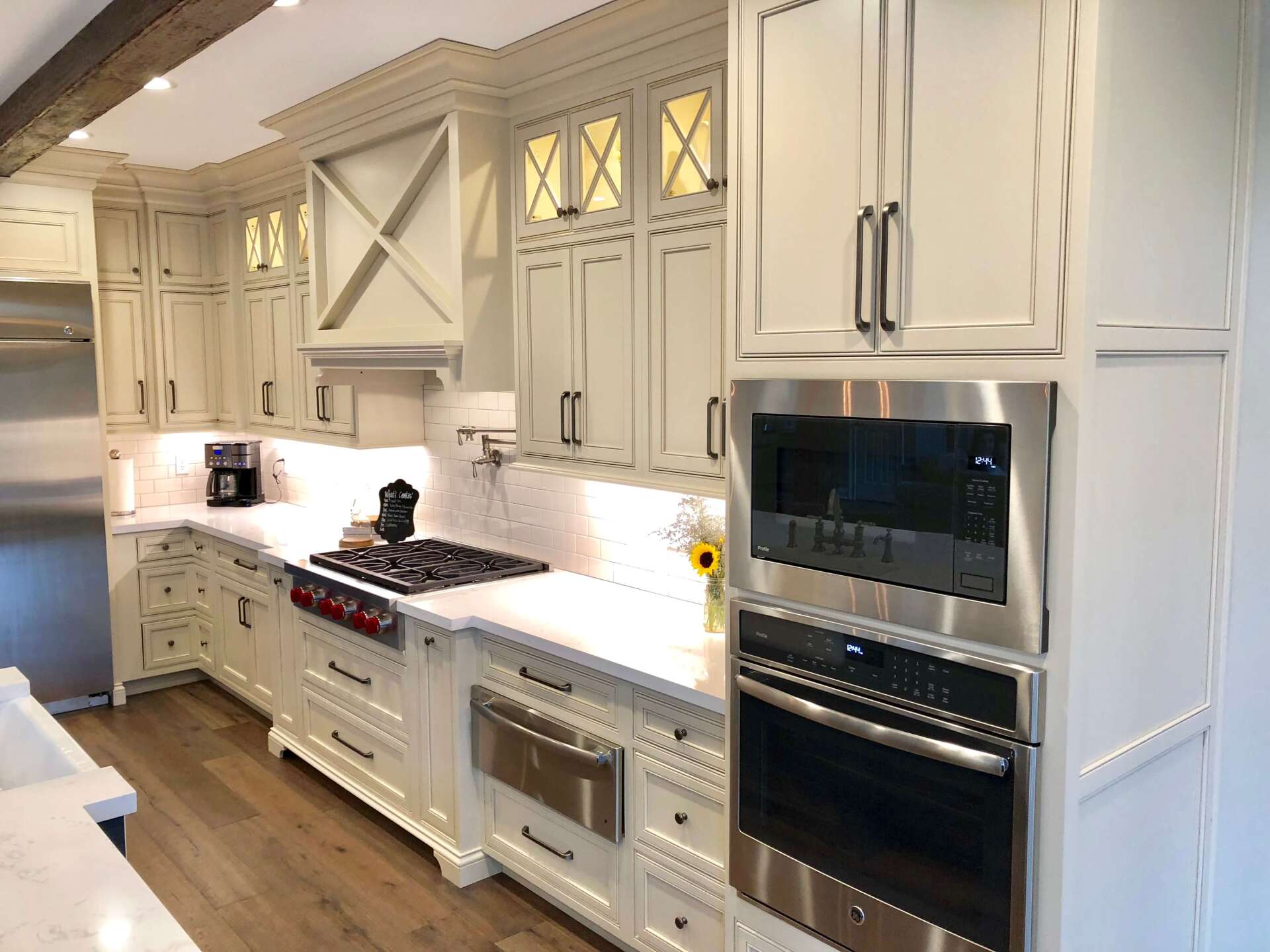 Elegant white kitchen with marble countertops, gas range, and built-in double oven