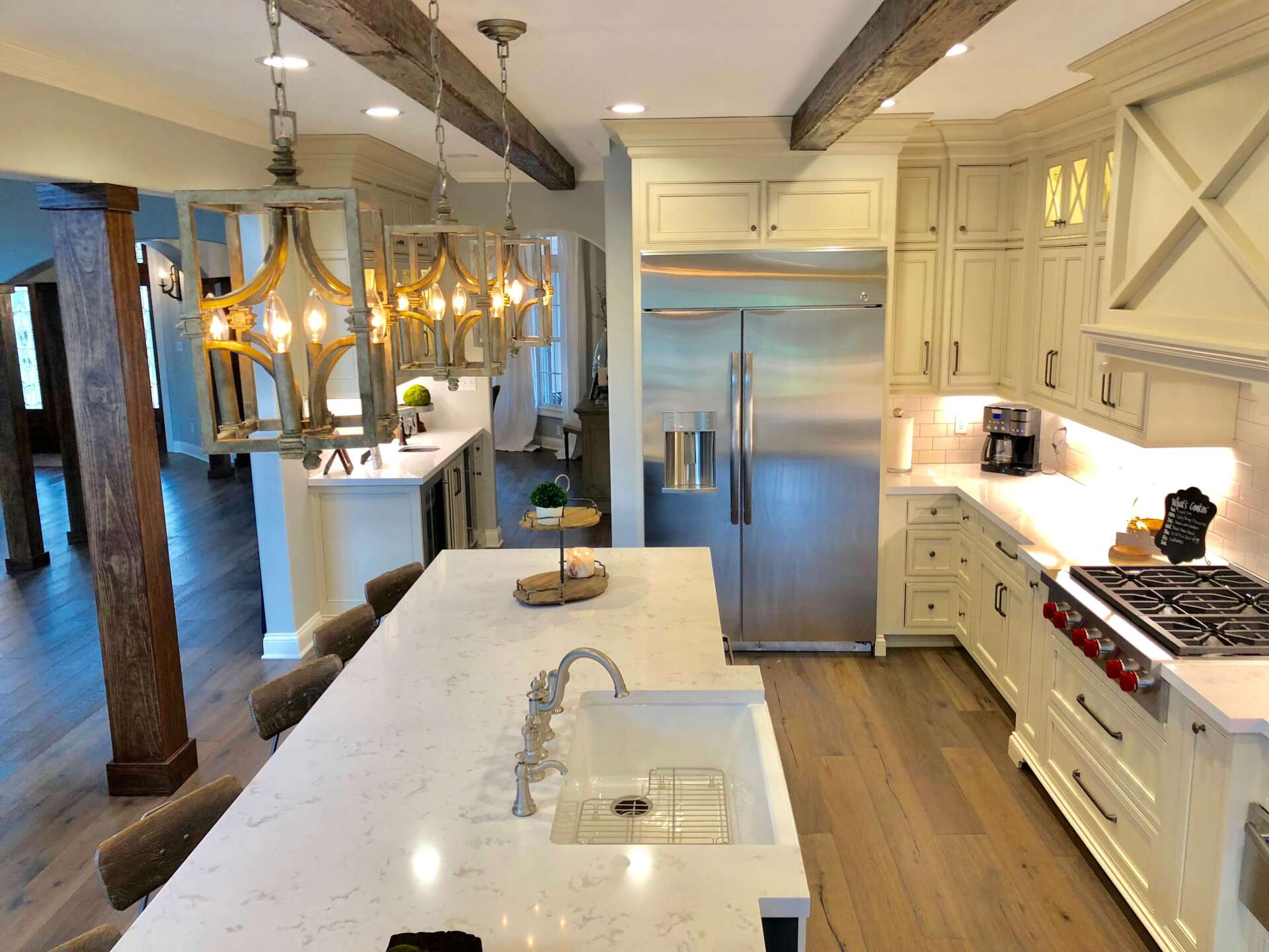 Bright modern kitchen with white cabinets, island, pendant lights, and stainless steel refrigerator