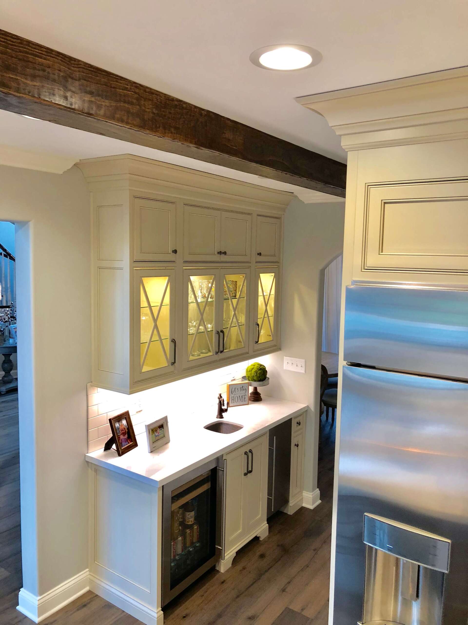 Bright kitchen nook with white cabinets, a wood beam ceiling, and a stainless steel refrigerator.