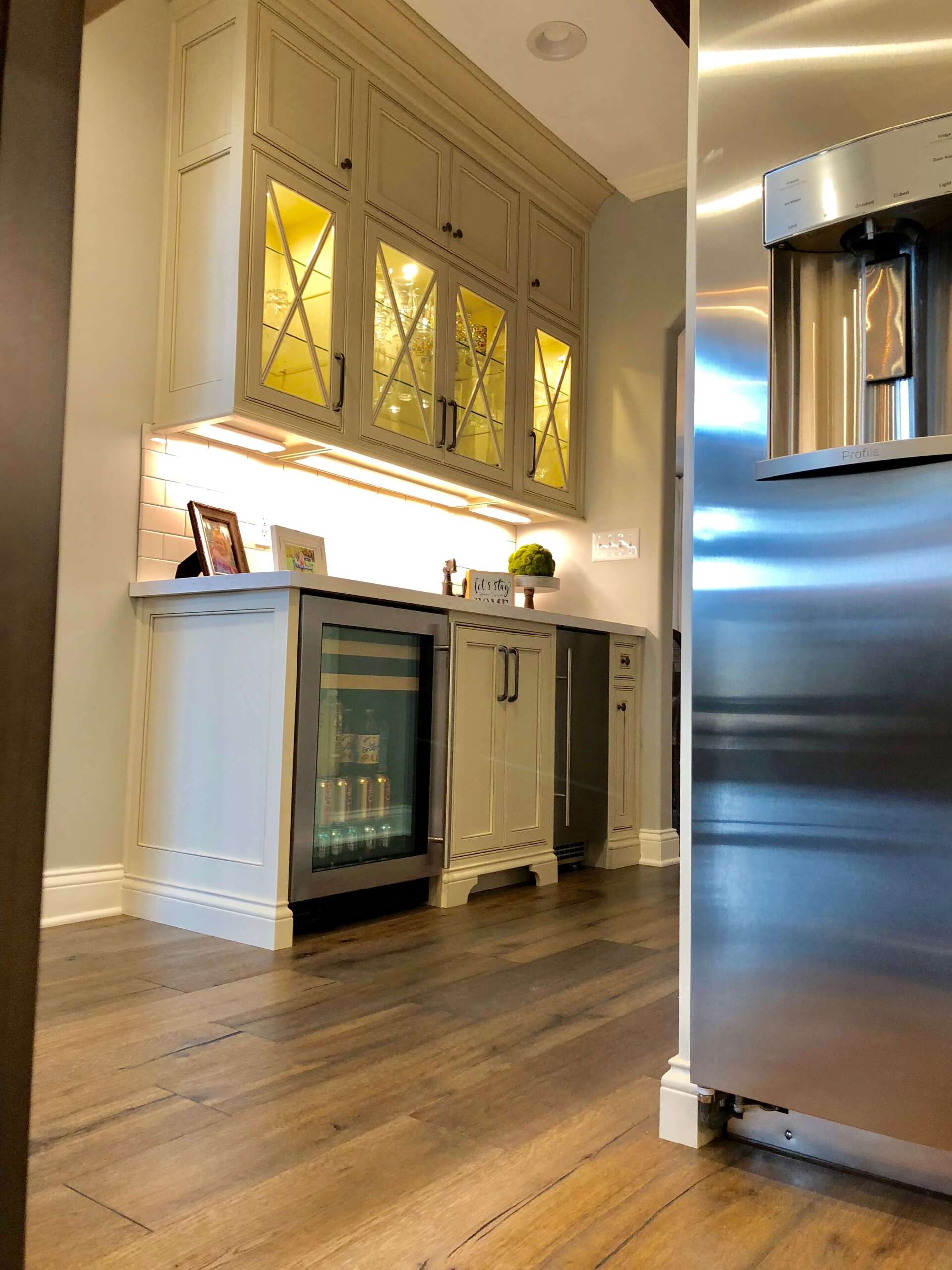 Kitchen with white cabinets, dark wood floor, and stainless-steel refrigerator in the foreground
