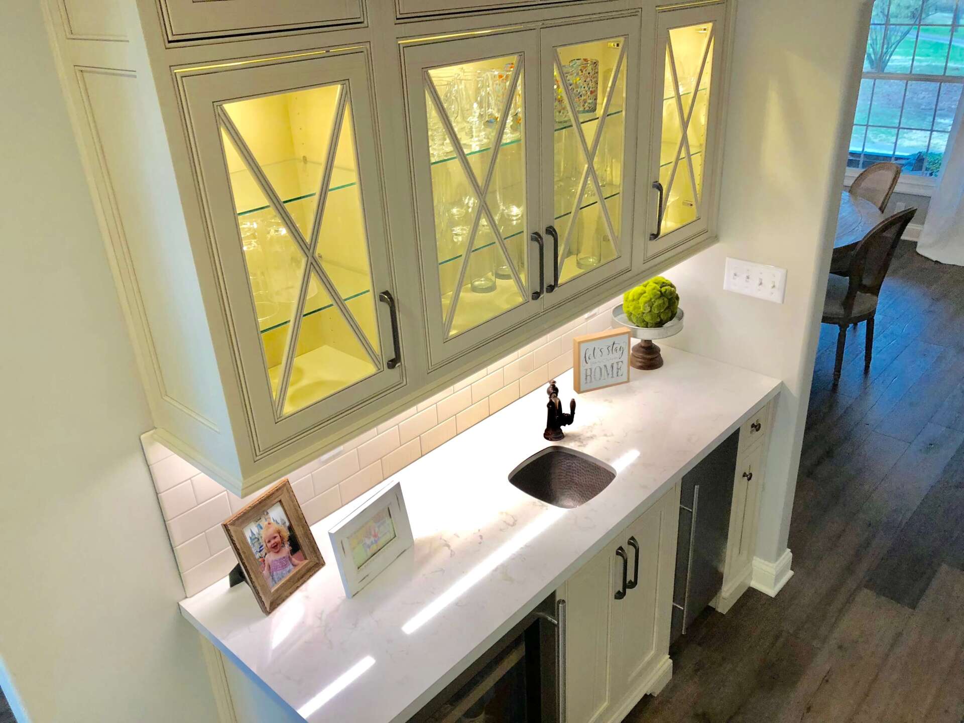 Bright bathroom vanity with double sinks, large mirror, framed photos, and a small plant on the counter