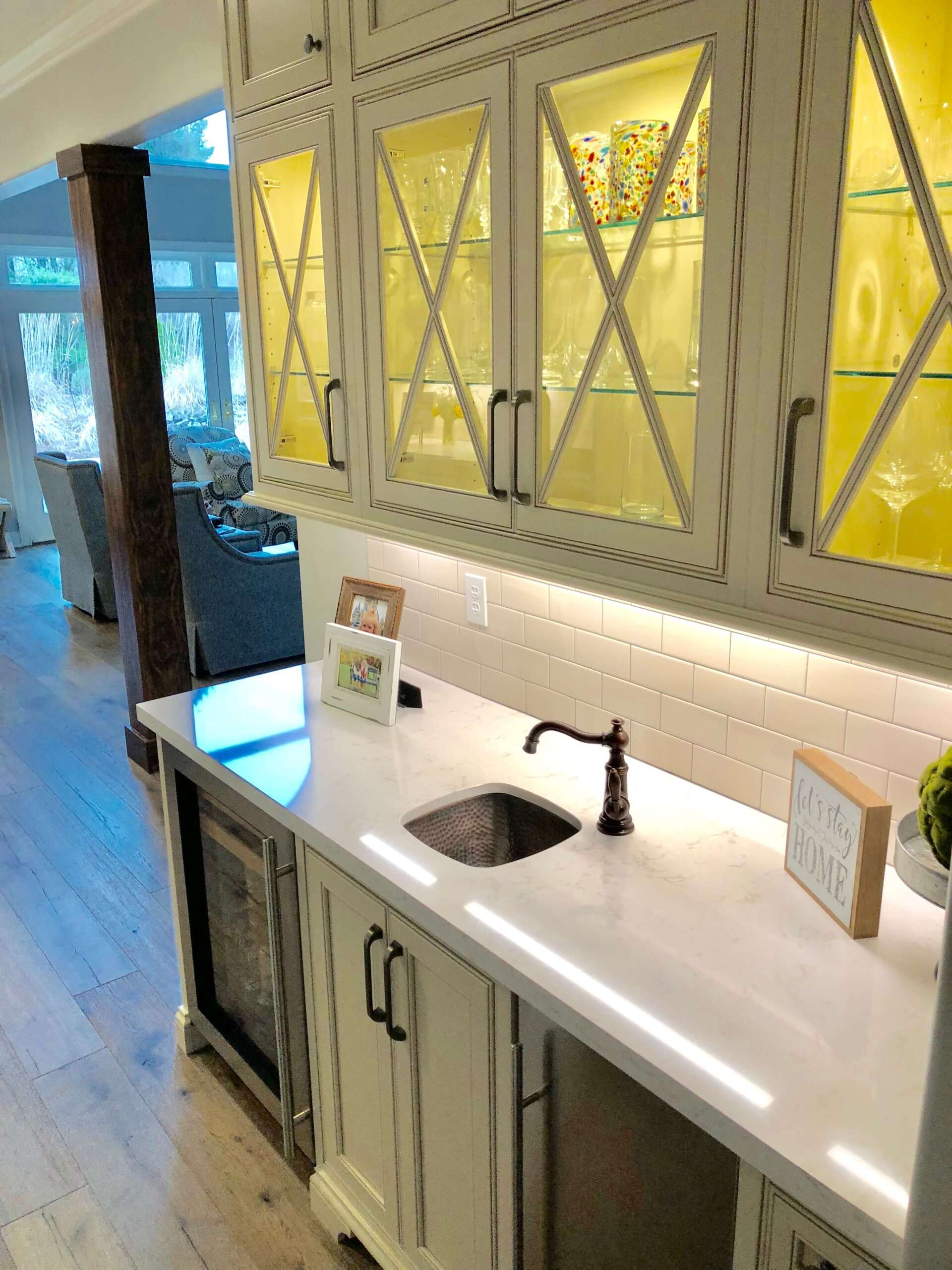 Bright kitchen with white cabinets, black hardware, and a white countertop with sink and faucet.