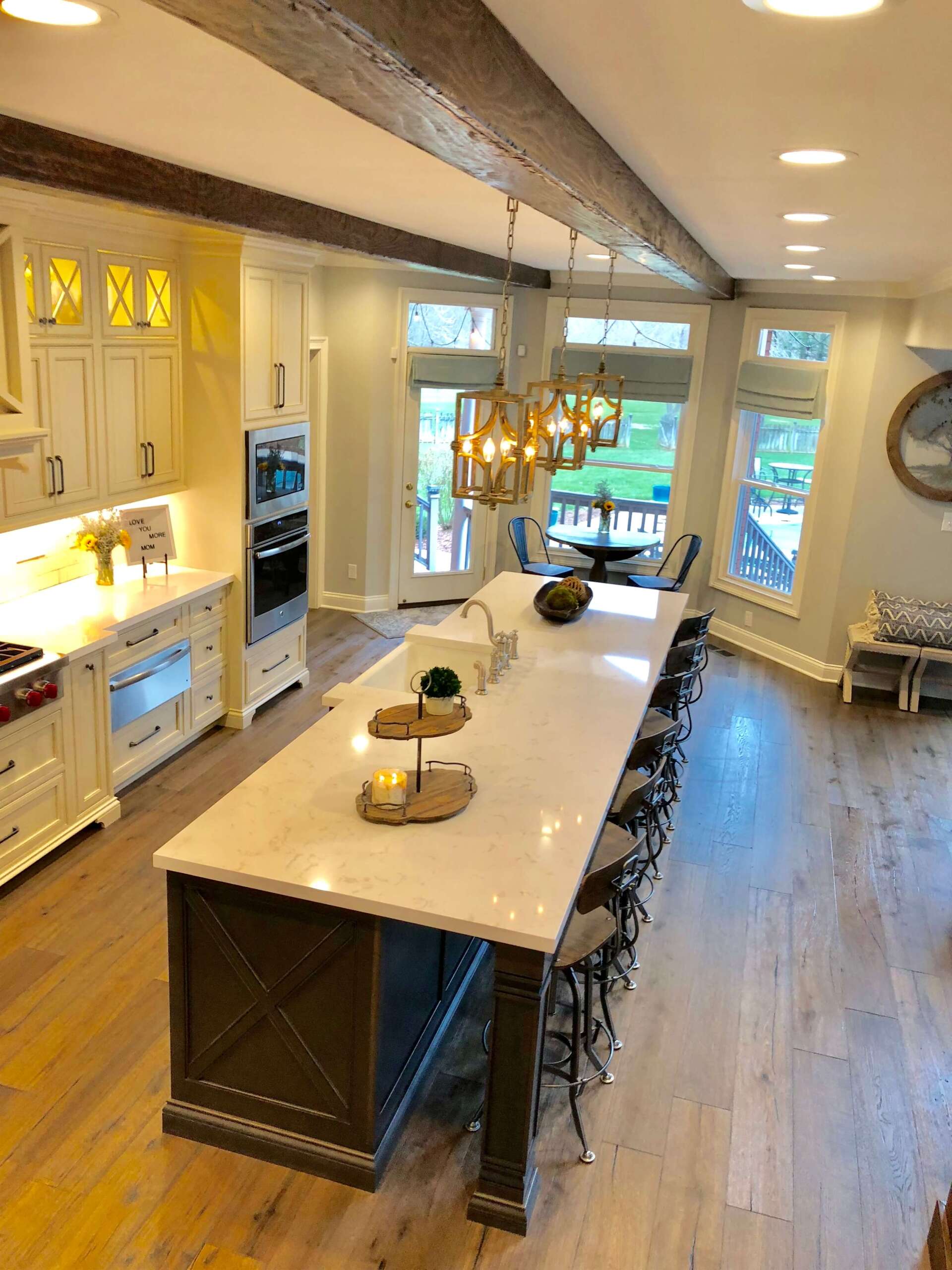 Bright modern kitchen with a large island, bar stools, pendant lights, and big windows overlooking greenery