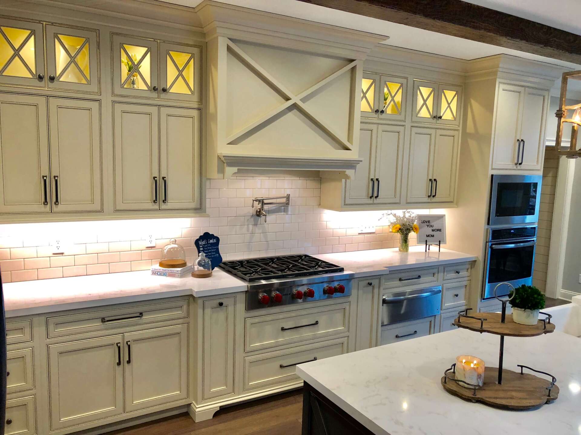 Bright white modern kitchen with cabinets, stainless appliances, and a large island table.
