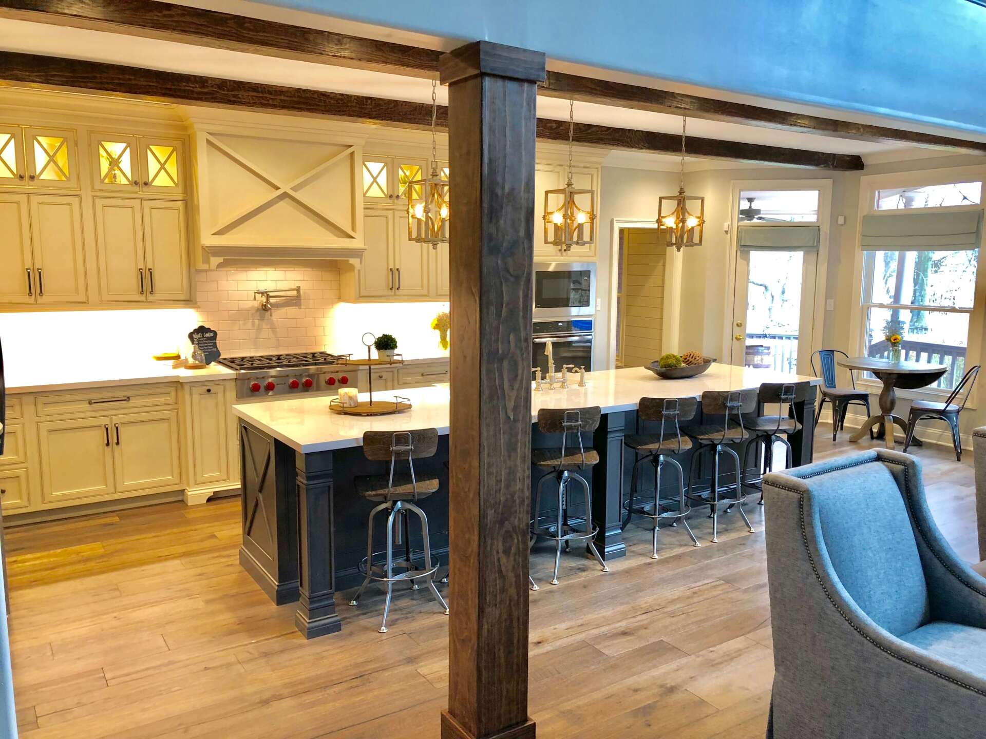Spacious farmhouse kitchen with white cabinets, dark island, barstools, and wood floors