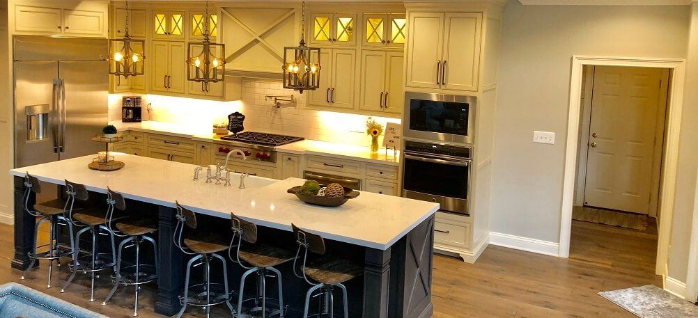 Modern kitchen with a large island, stools, pendant lights, and a doorway to a hallway
