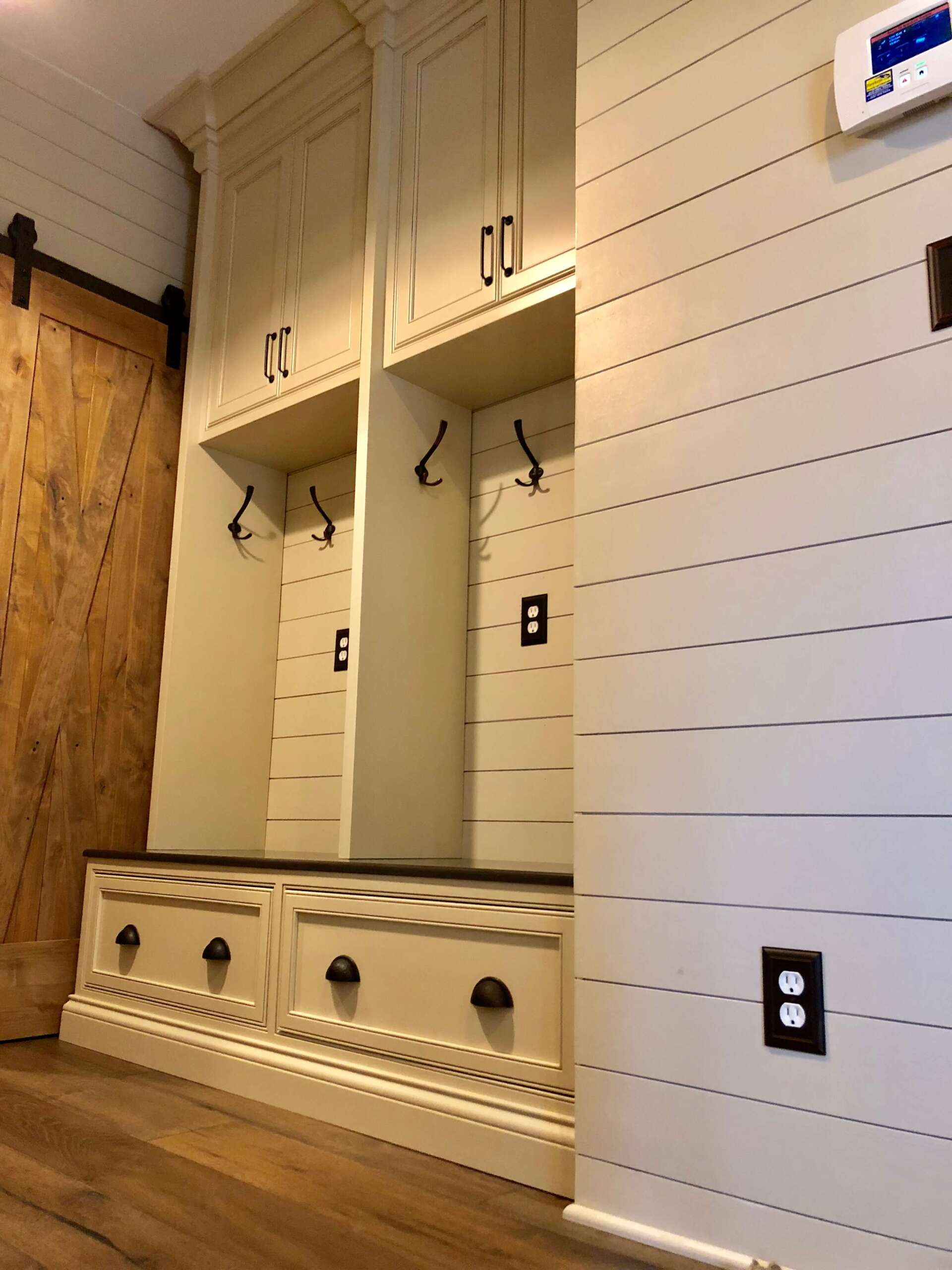 Locker room with white built-in lockers, benches, hooks, and wood flooring.