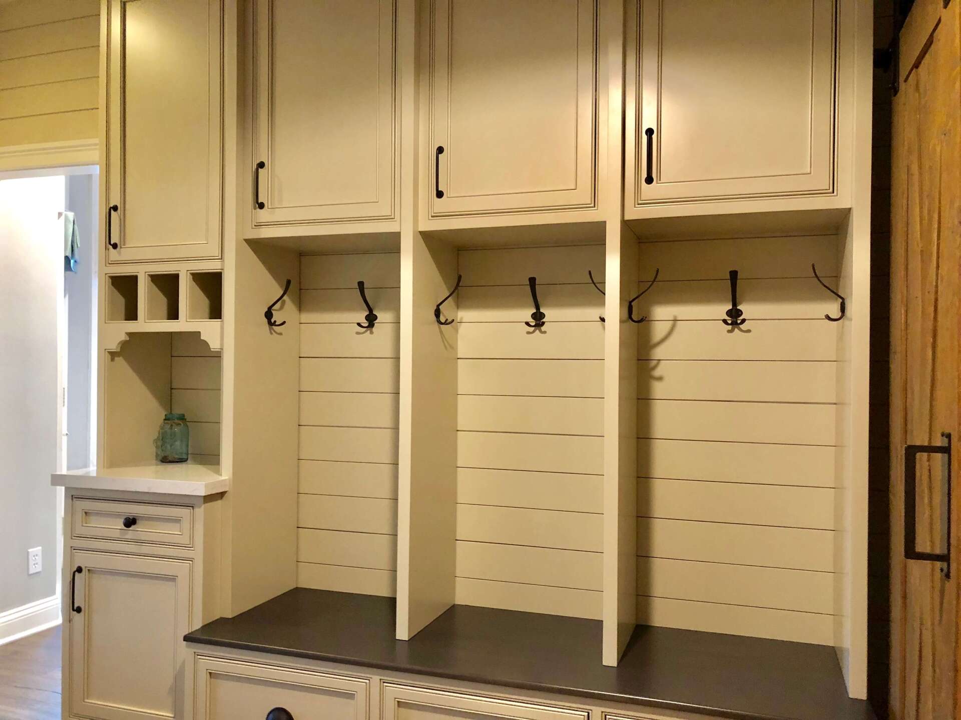 Built-in mudroom cubbies with hooks, shelves, and a bench in a light wood entryway