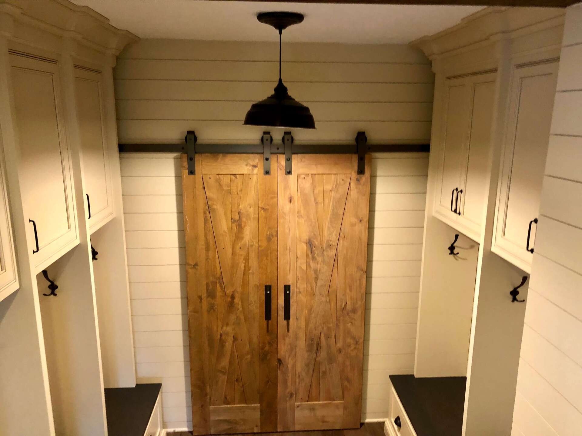 Walk-in closet with white cabinets, black countertops, and rustic wood barn doors under a ceiling light
