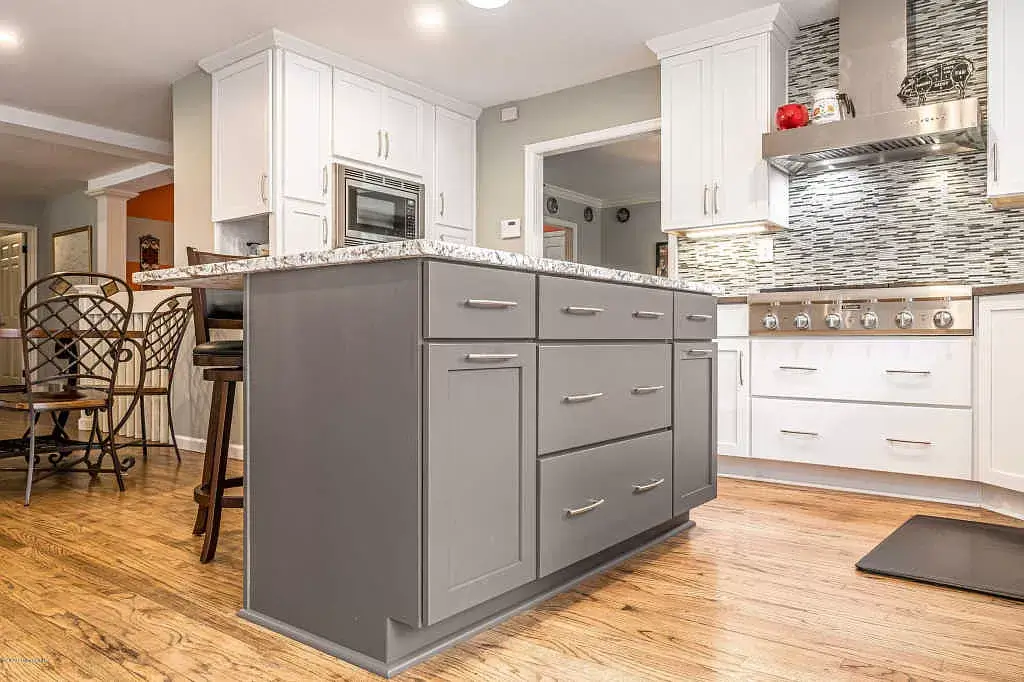 Modern kitchen with gray island, white cabinets, and wood floors