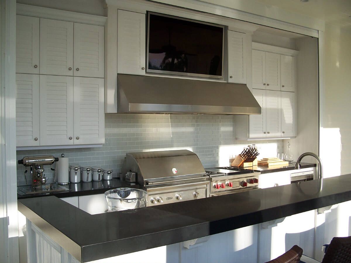 Modern kitchen with black island, stainless steel stove, white cabinets, and large range hood