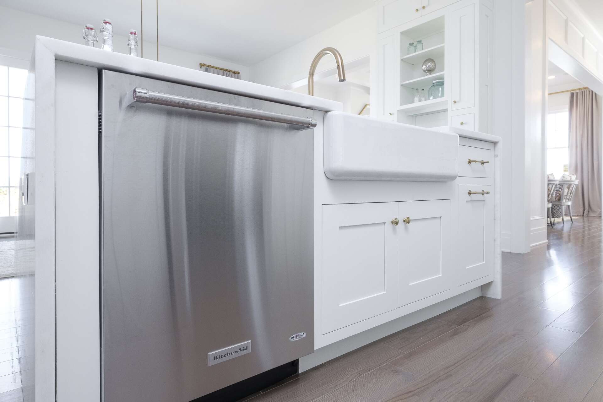 Modern white kitchen with a stainless-steel dishwasher in the foreground