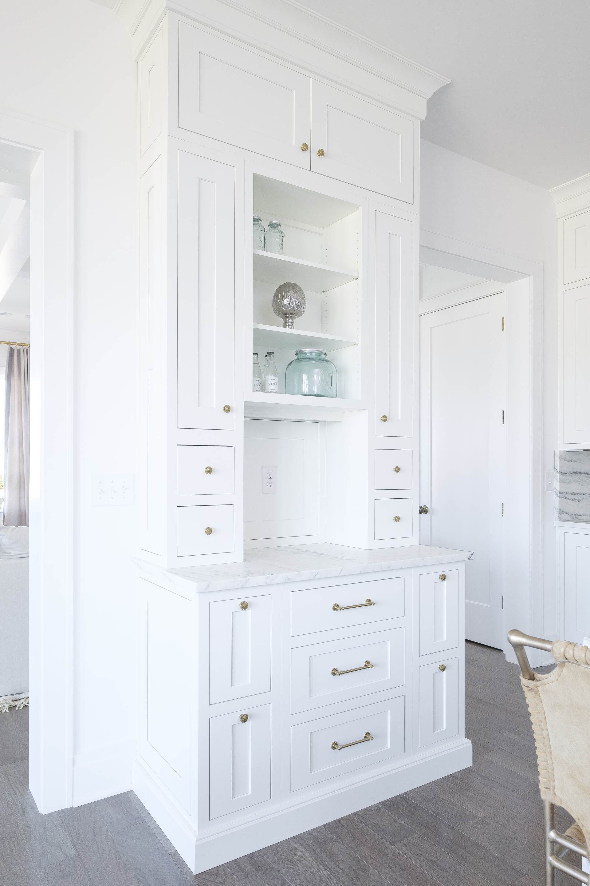 White built-in cabinet with drawers and glass shelves in a bright room