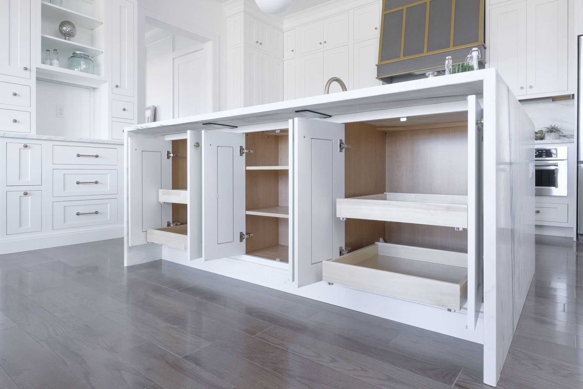 Bright white kitchen island with open cabinet doors and shelves on a dark wood floor.