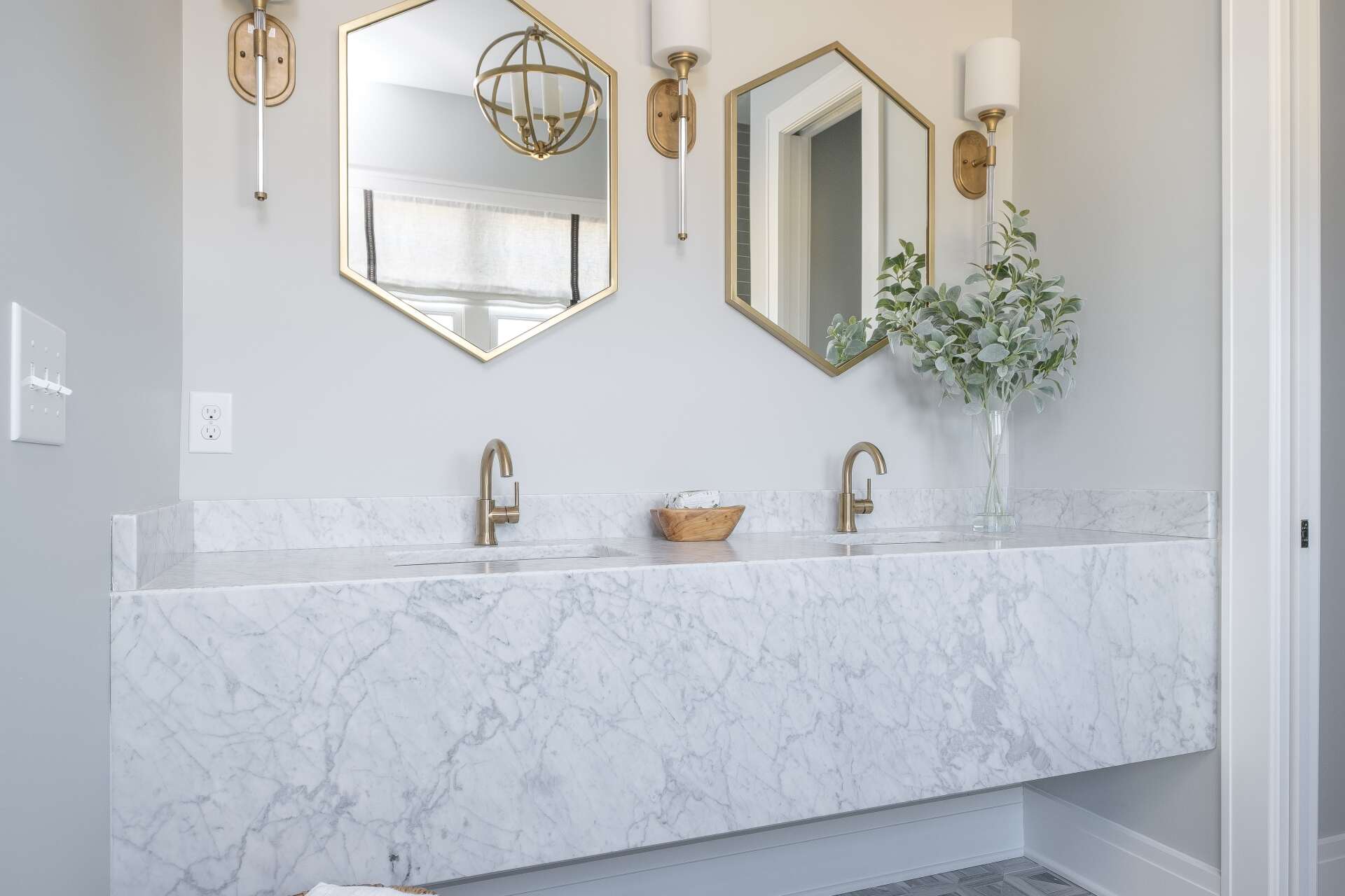 Modern bathroom vanity with double sinks, marble countertop, gold accents, and wall mirrors