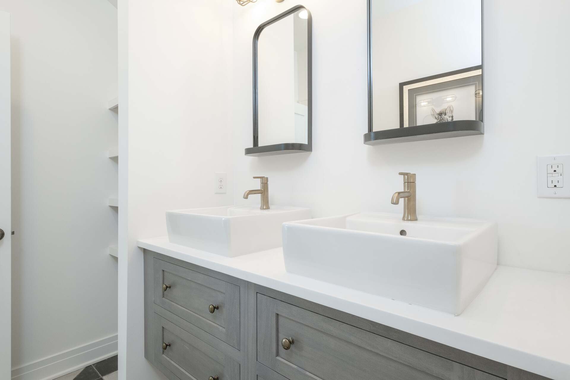 Modern bathroom vanity with double sinks, gray cabinets, and wall-mounted mirrors.