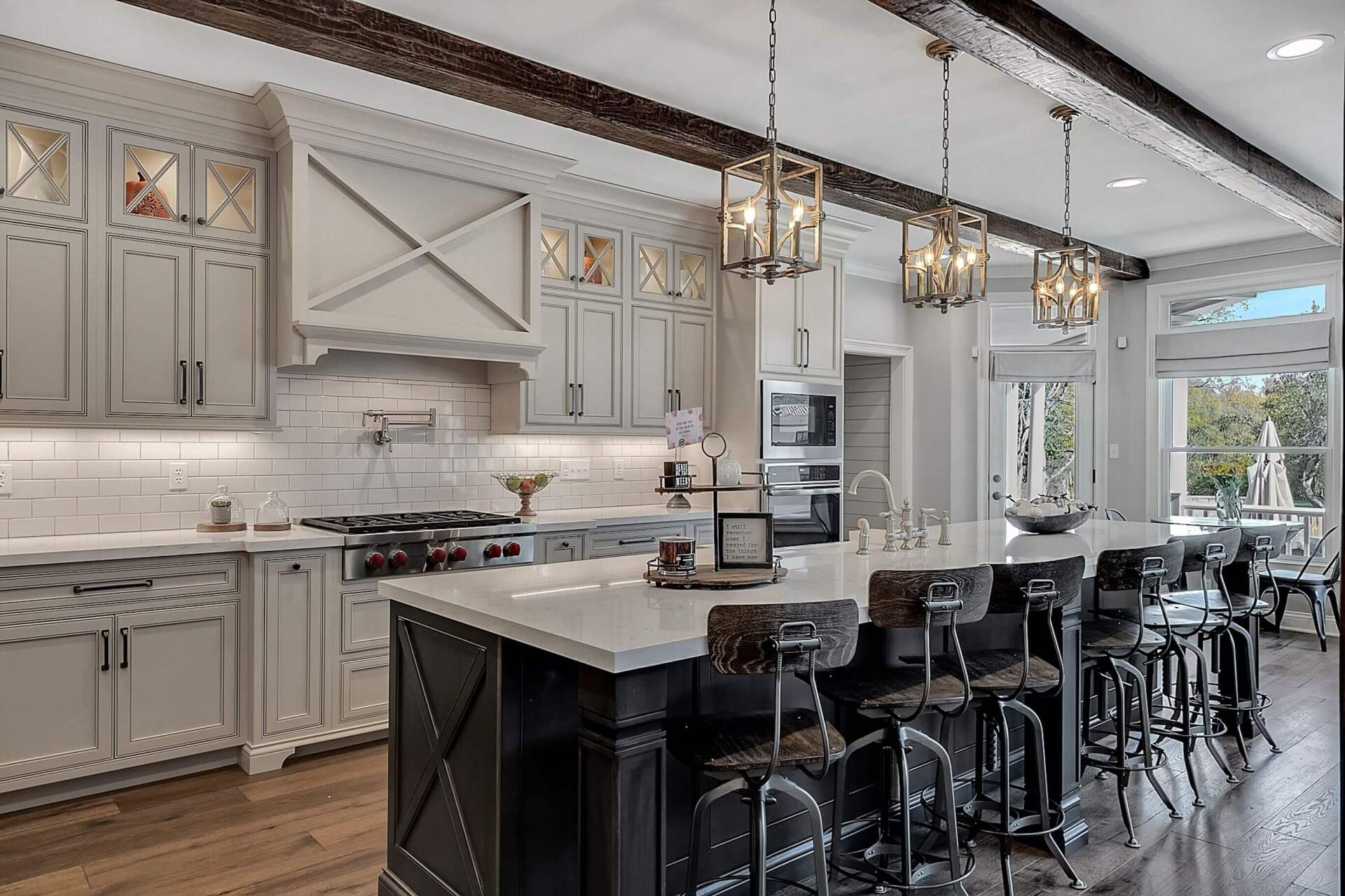 Bright modern kitchen with white cabinets, large island, and black bar stools under pendant lights