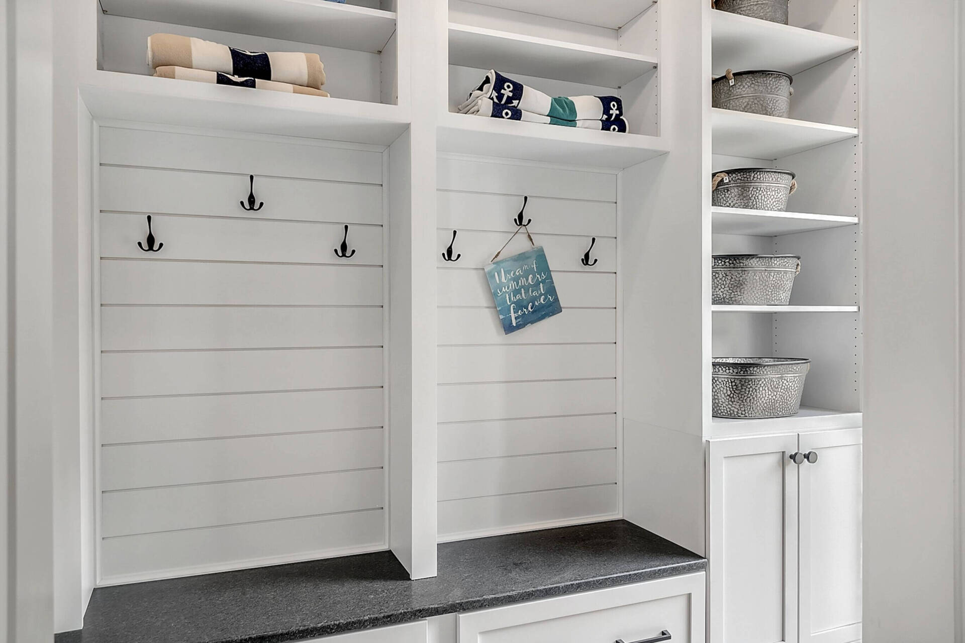 White mudroom cubbies with hooks, baskets, and built-in storage drawers in a bright room