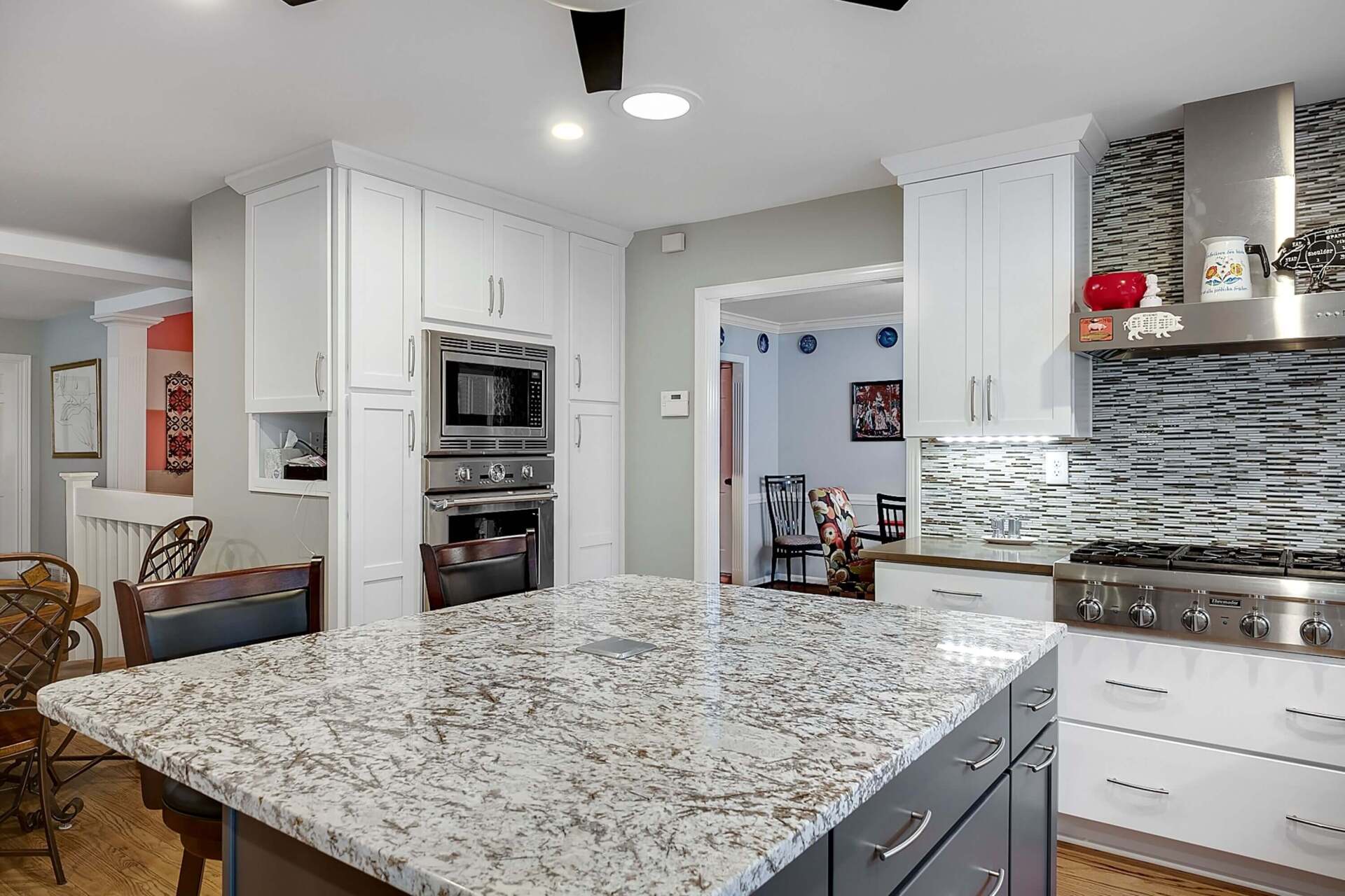 Bright modern kitchen with granite island, white cabinets, and mosaic backsplash