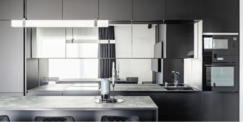 Modern kitchen with dark cabinetry, marble island, and large window reflecting the room