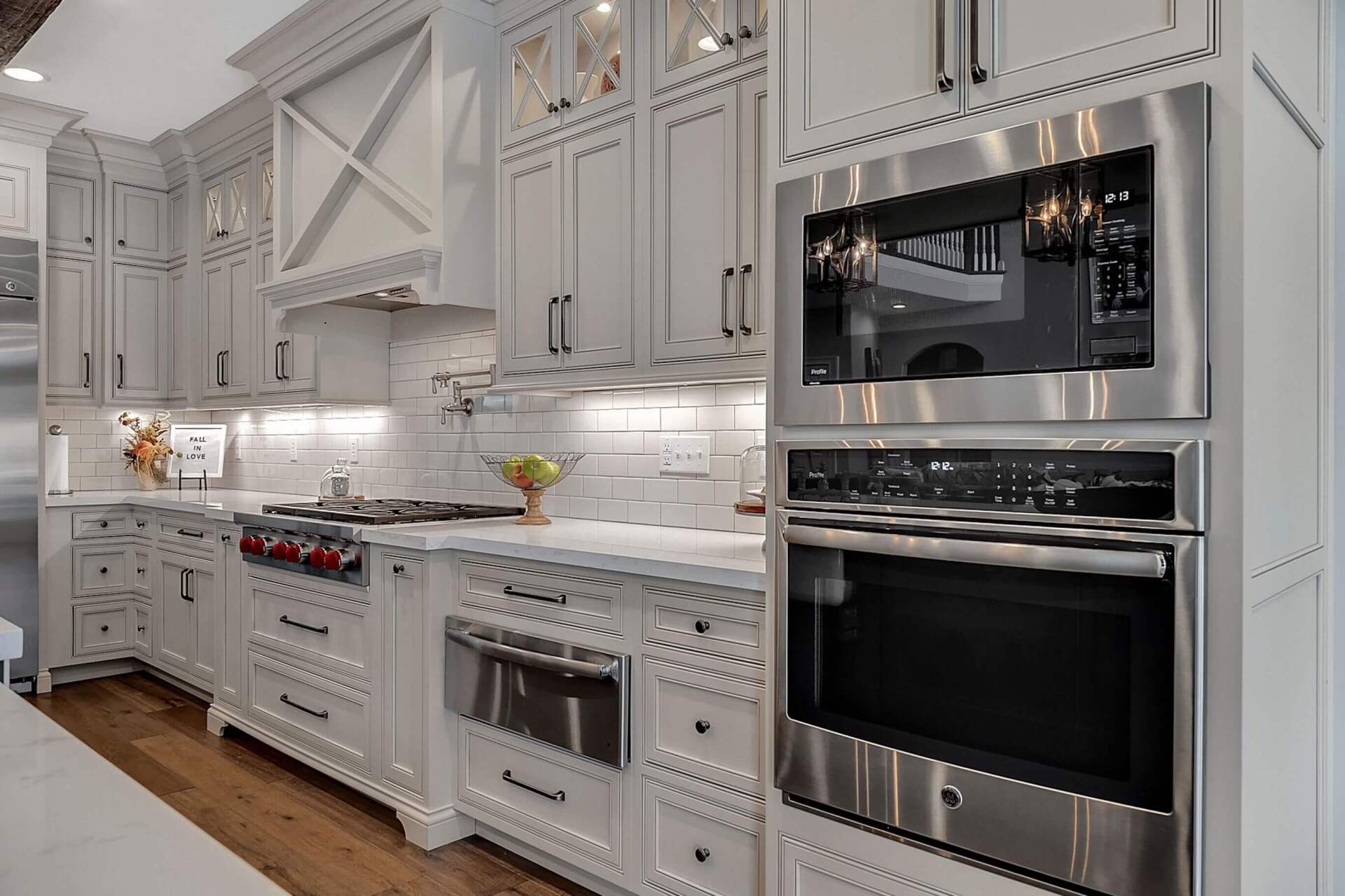 Bright white luxury kitchen with stainless steel appliances, marble counters, and subway tile backsplash