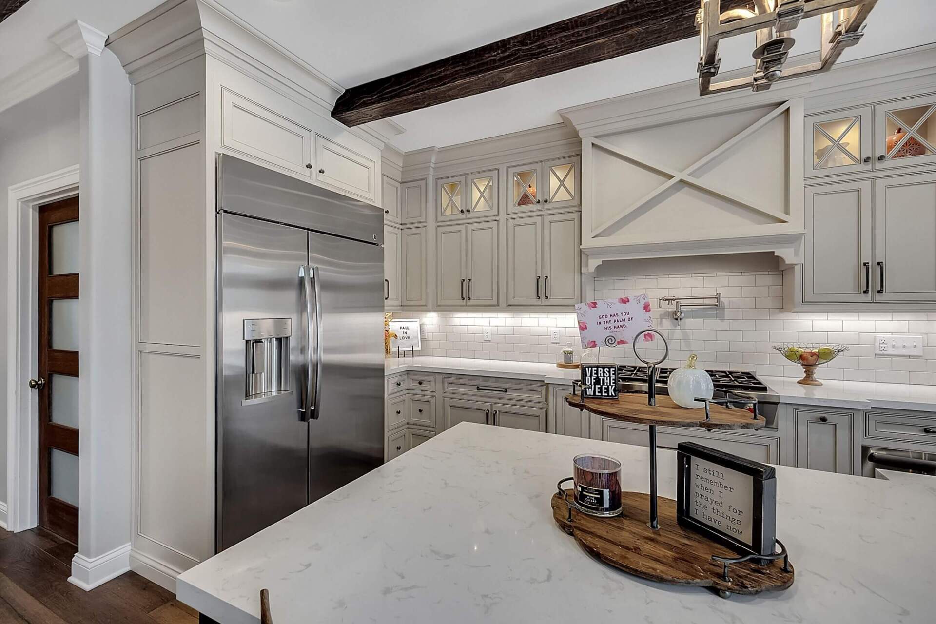 Bright white modern kitchen with marble island, stainless fridge, and gray cabinets