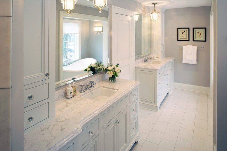 Bright white bathroom with double vanity, large mirror, marble countertops, and tiled floor