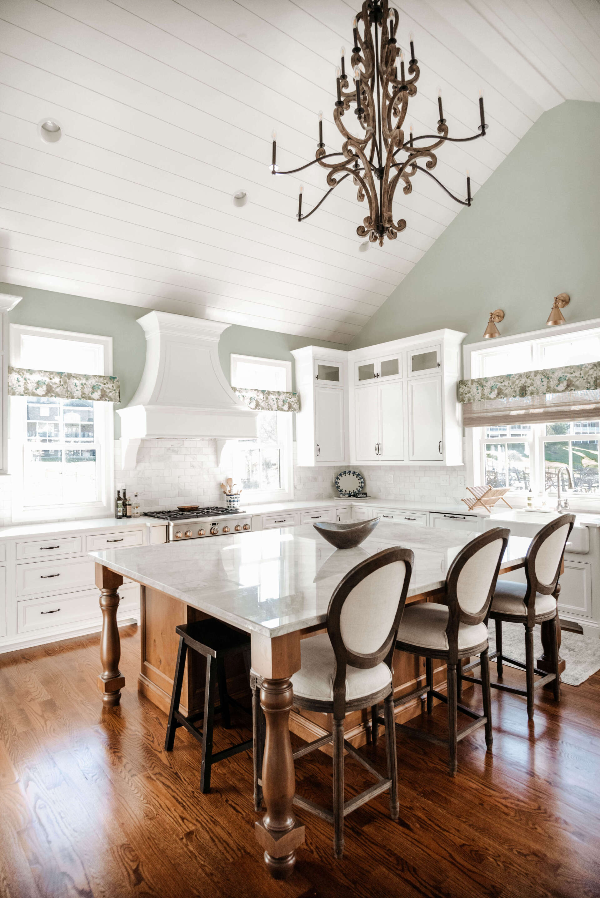 Bright kitchen with white cabinets, island, dark wood floors, and a chandelier under a vaulted ceiling