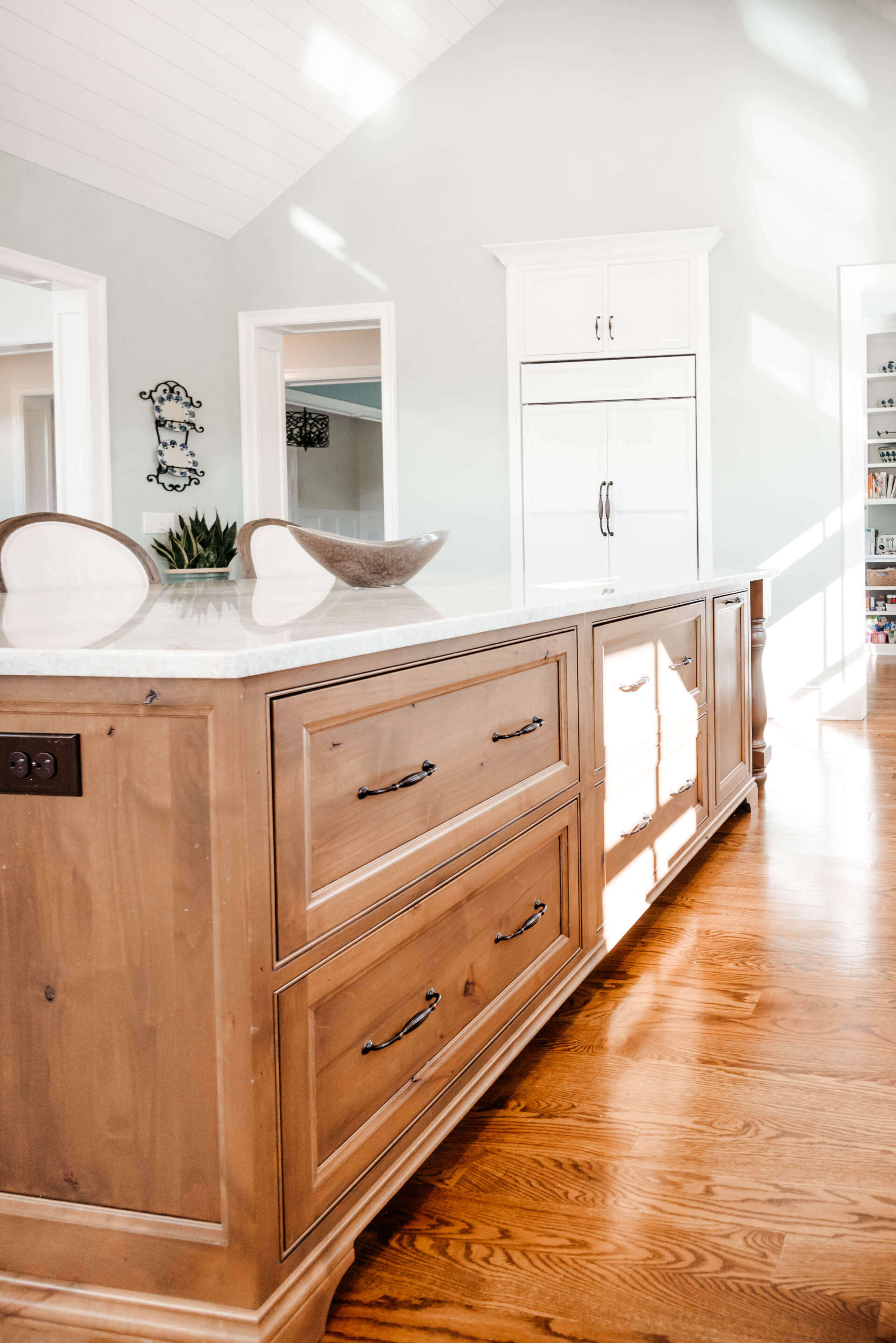 Bright kitchen with a large wooden island, white cabinets, and sunlit hardwood floors