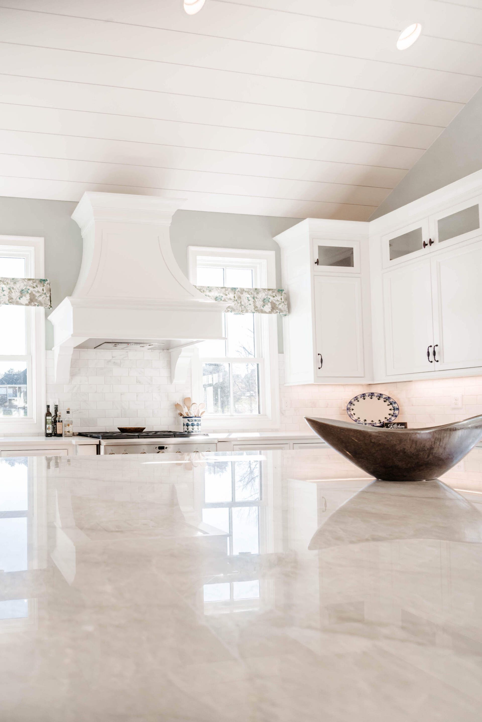 Bright white modern kitchen with glossy marble floor and large bowl on the island